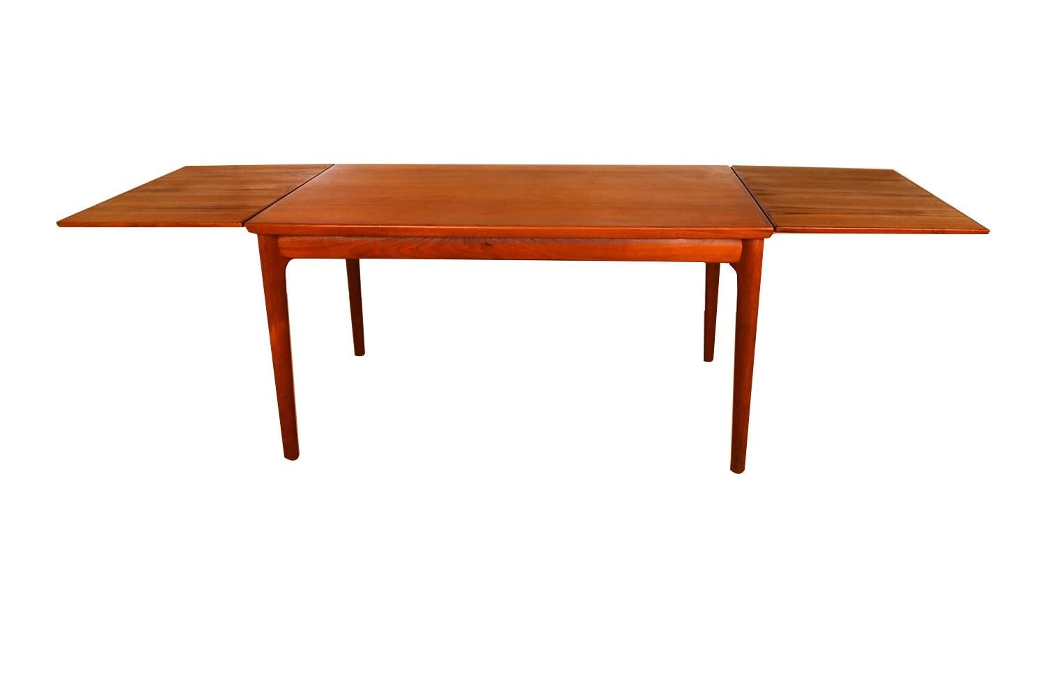 Exceptional Danish modern teak extension dining table. This gorgeous Danish Teak extending dining table remains in original excellent condition throughout. With an initial medium footprint, this table can also offer a generous space and double in