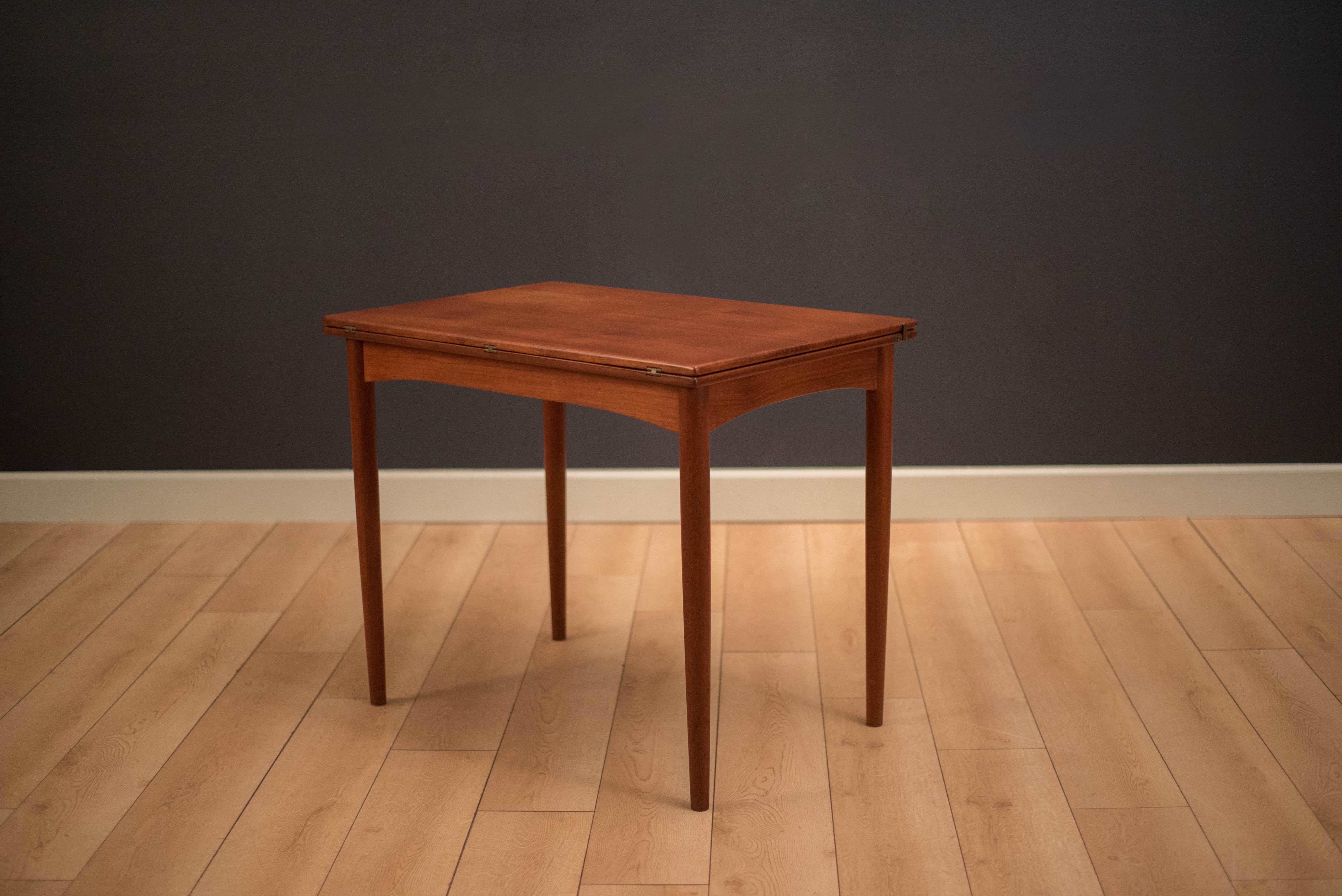 Mid-Century Modern flip-top dining table designed by Borge Mogensen for Soborg Mobler. This versatile piece is finished in teak with the designer's custom brass hardware. Tabletop folds over to increase the surface area and can seat up to four.