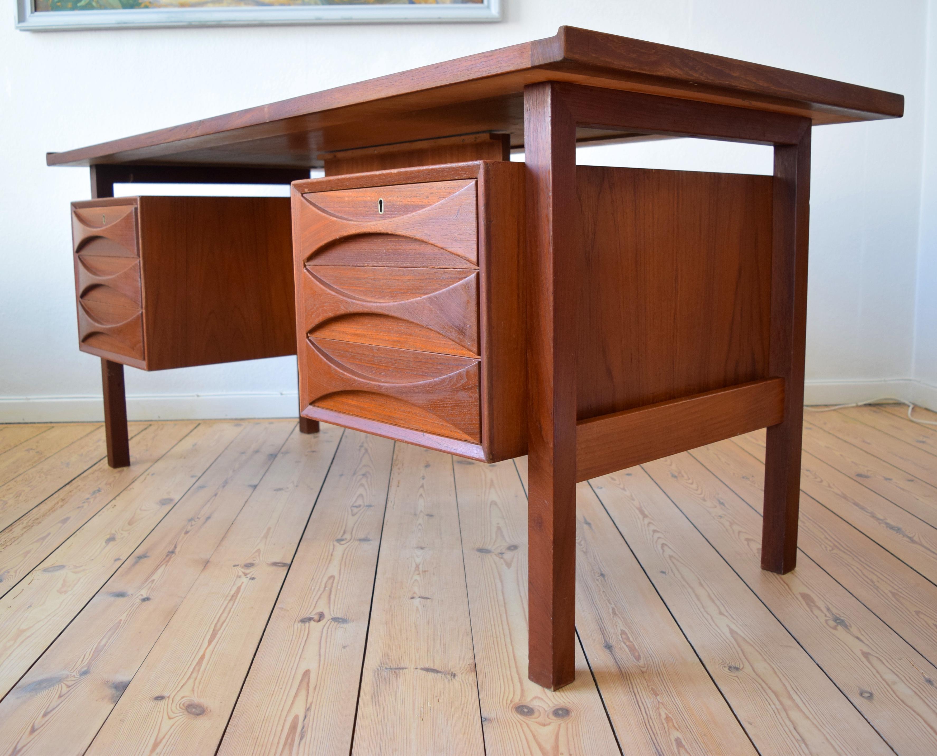 Executive floating desk in teak manufactured in Denmark in the 1960s. Featured six drawers (two lockable) on the front with solid teak drawer pulls. Three compartments on the rear can be used as storage for books. Solid teak edge on the top-plate