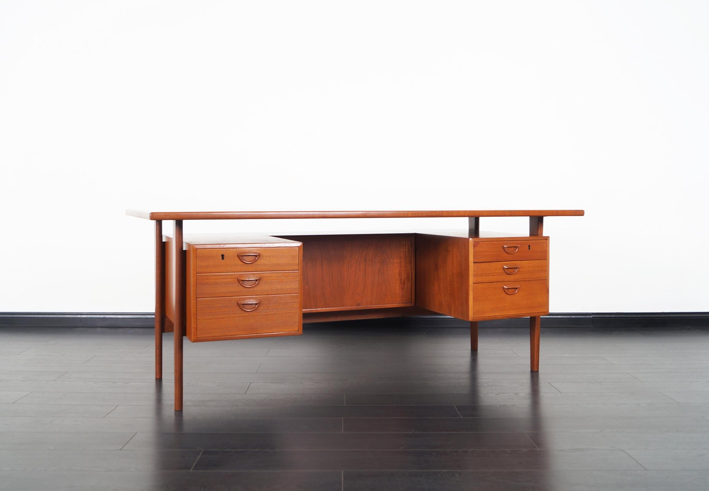 Amazing danish teak executive desk designed by Kai Kristiansen for Feldballes Møbelfrabrik, model FM 60. This freestanding desk features a floating top, six dovetailed drawers in the front, at the rear two extra storage units, and a open space for