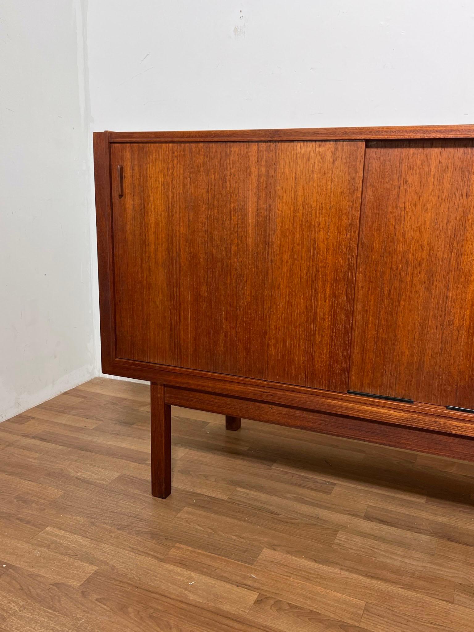 Large 7.25 foot long Danish teak credenza featuring four sliding doors, with adjustable shelving and shallow felt-lined drawers. Marked made in Denmark, in the style of Ib Kofod-Larsen.