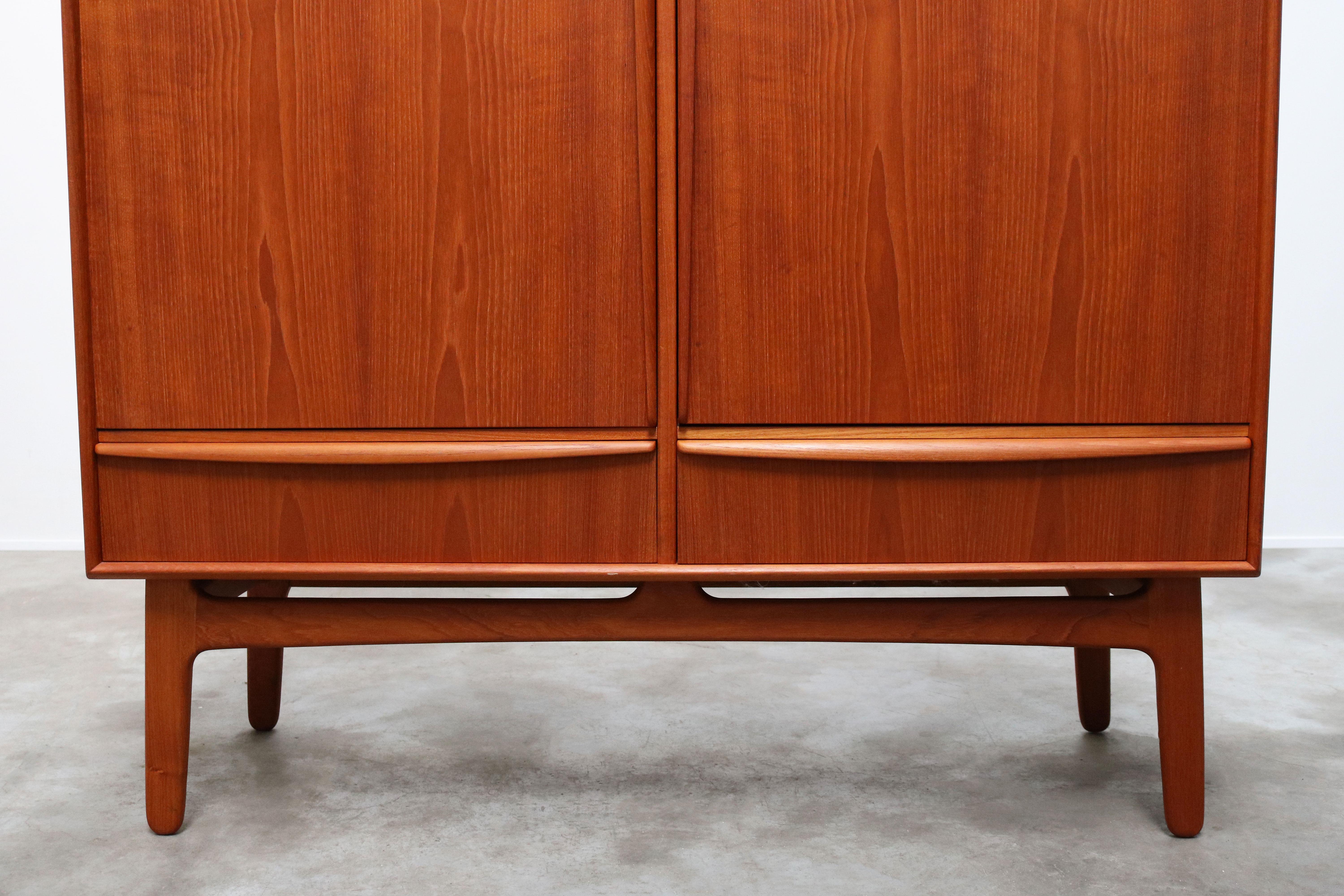 Magnificent Danish design highboard / cabinet designed by Svend Aage Madsen for K. Knudsen & son in the 1950s. Wonderful design with organic sculpted grips and base in solid teak. The cabinet has 2 drawers and multiple adjustable shelves , the