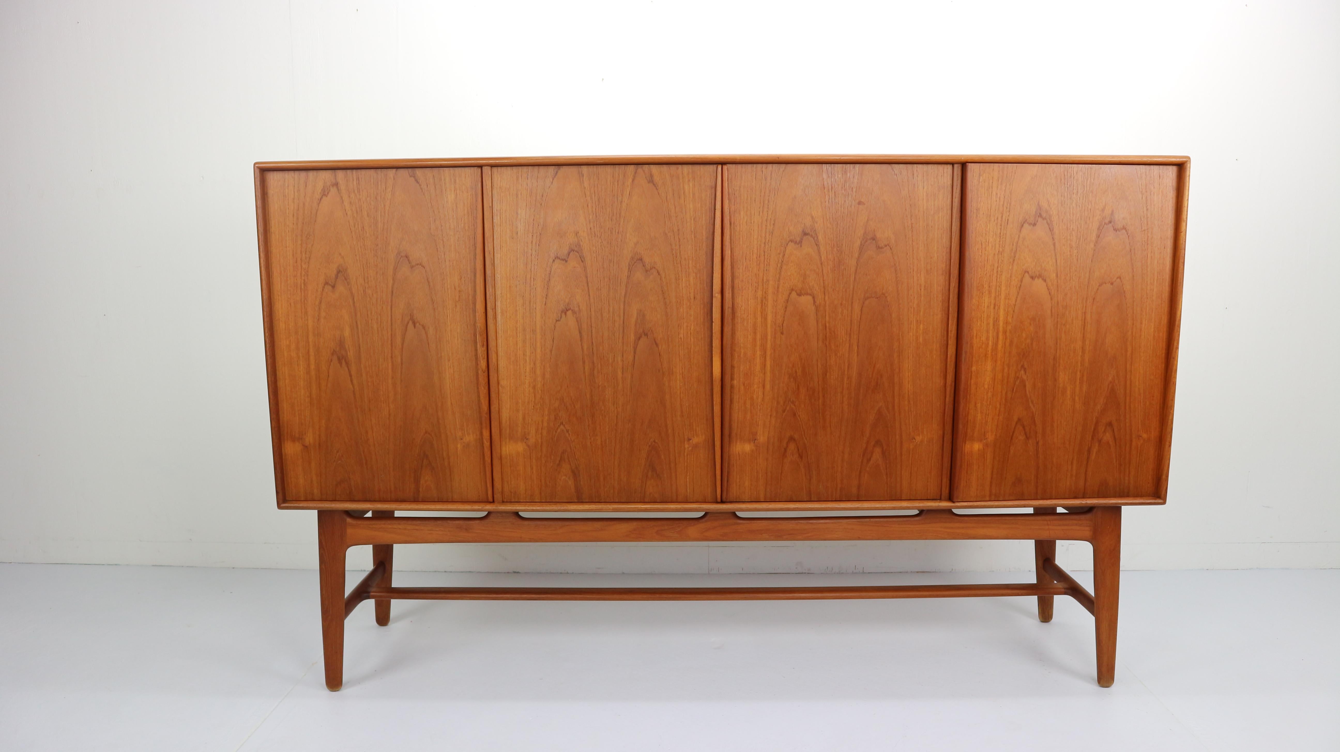 Rare model Danish highboard or cabinet designed by Svend Aage Madsen for K. Knudsen & Son in the 1950s. It's a wonderful solid teak design with organically sculpted grips and elegant curves. The entire interior is finished in teak and looks