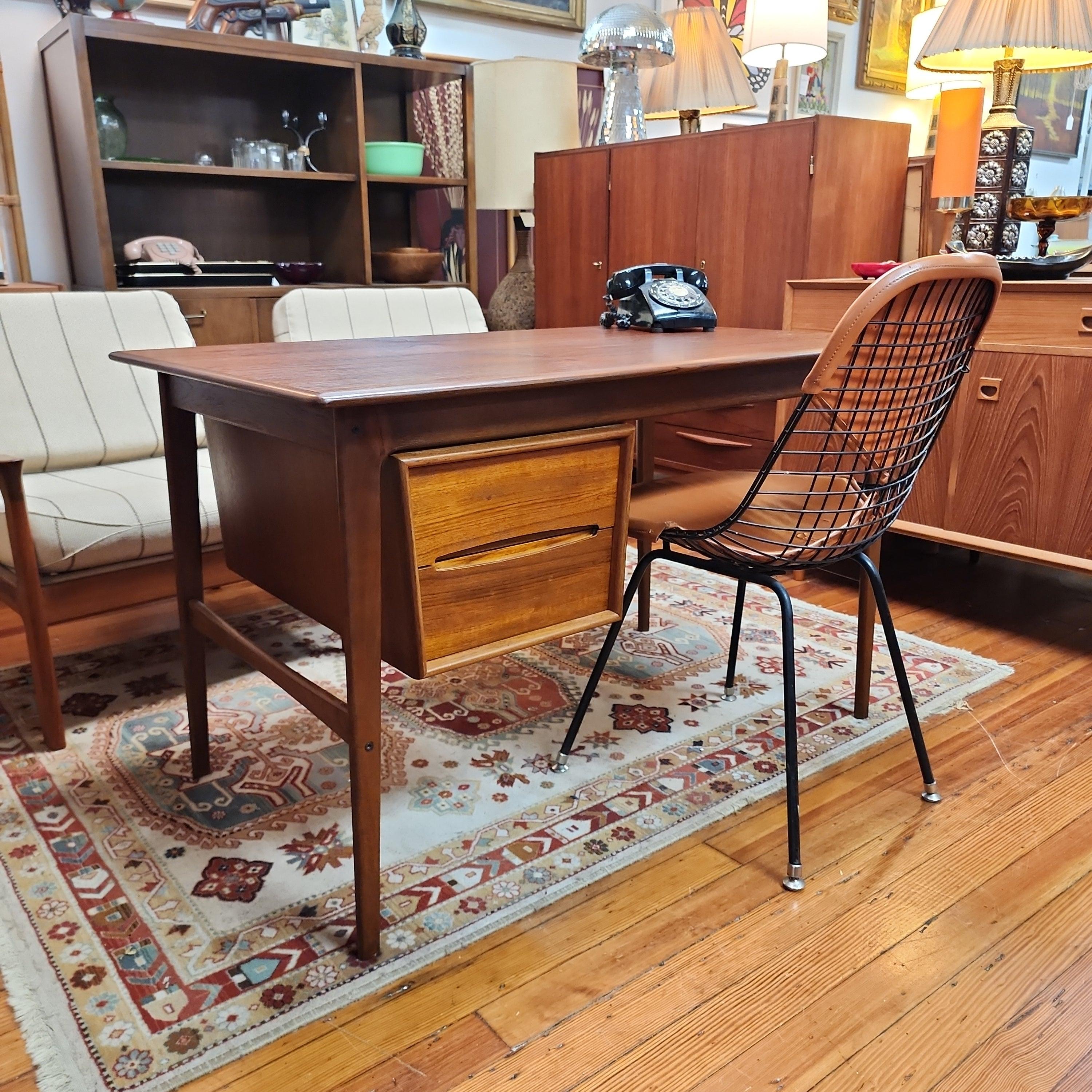 This unusual Danish teak writing desk has a special design. The drawer stack can slide from left to right to accommodate different spaces and left-handed individuals. 
The deep red tone of the teak dates this piece to the 1950s with its beautiful