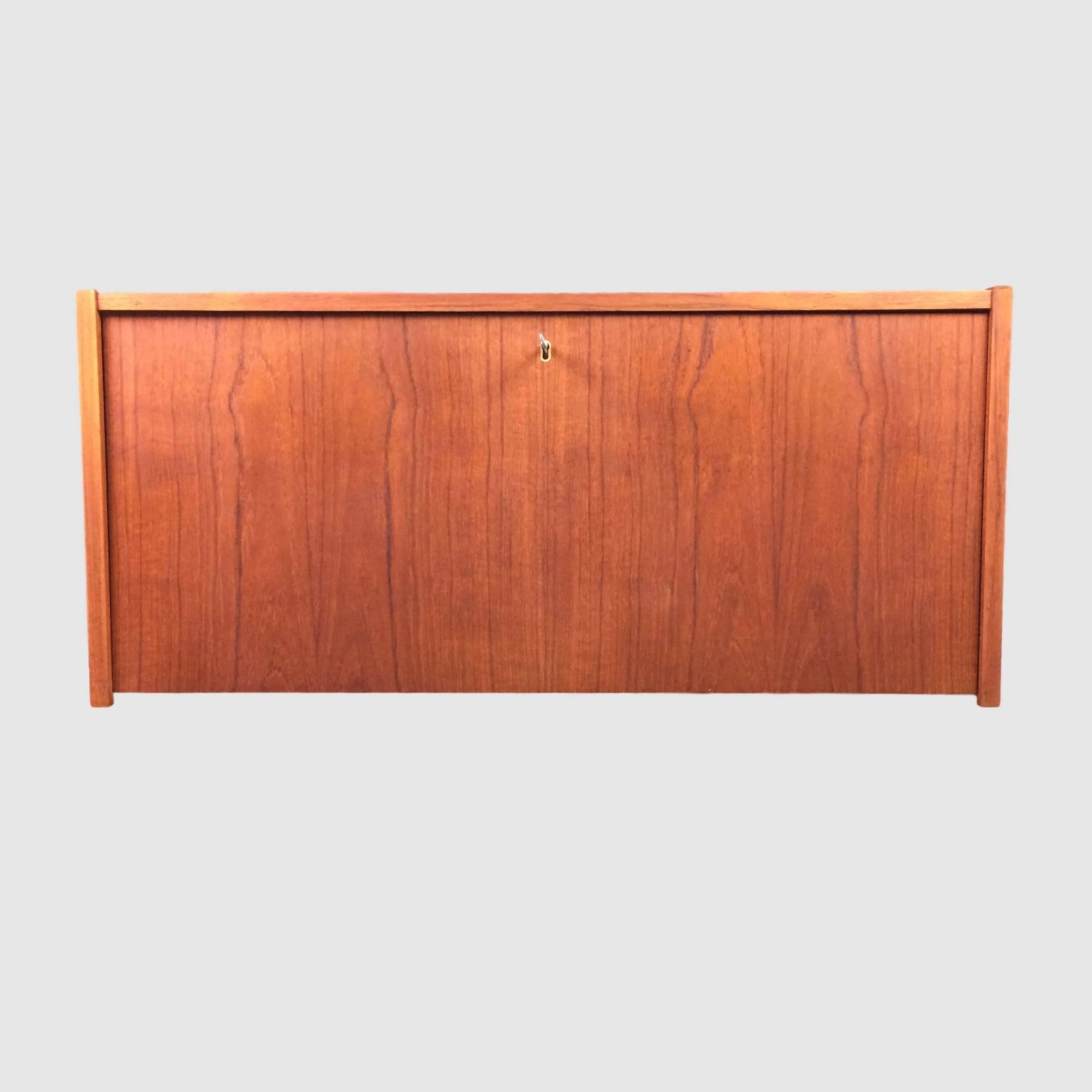 Incredibly beautiful and well maintained Danish designed mini bar in teak veneer. 

The bar has two small shelves inside, which is fitted with small brass studs. 
Door can be tilted down and is held in place with a brass locking mechanism. 
The