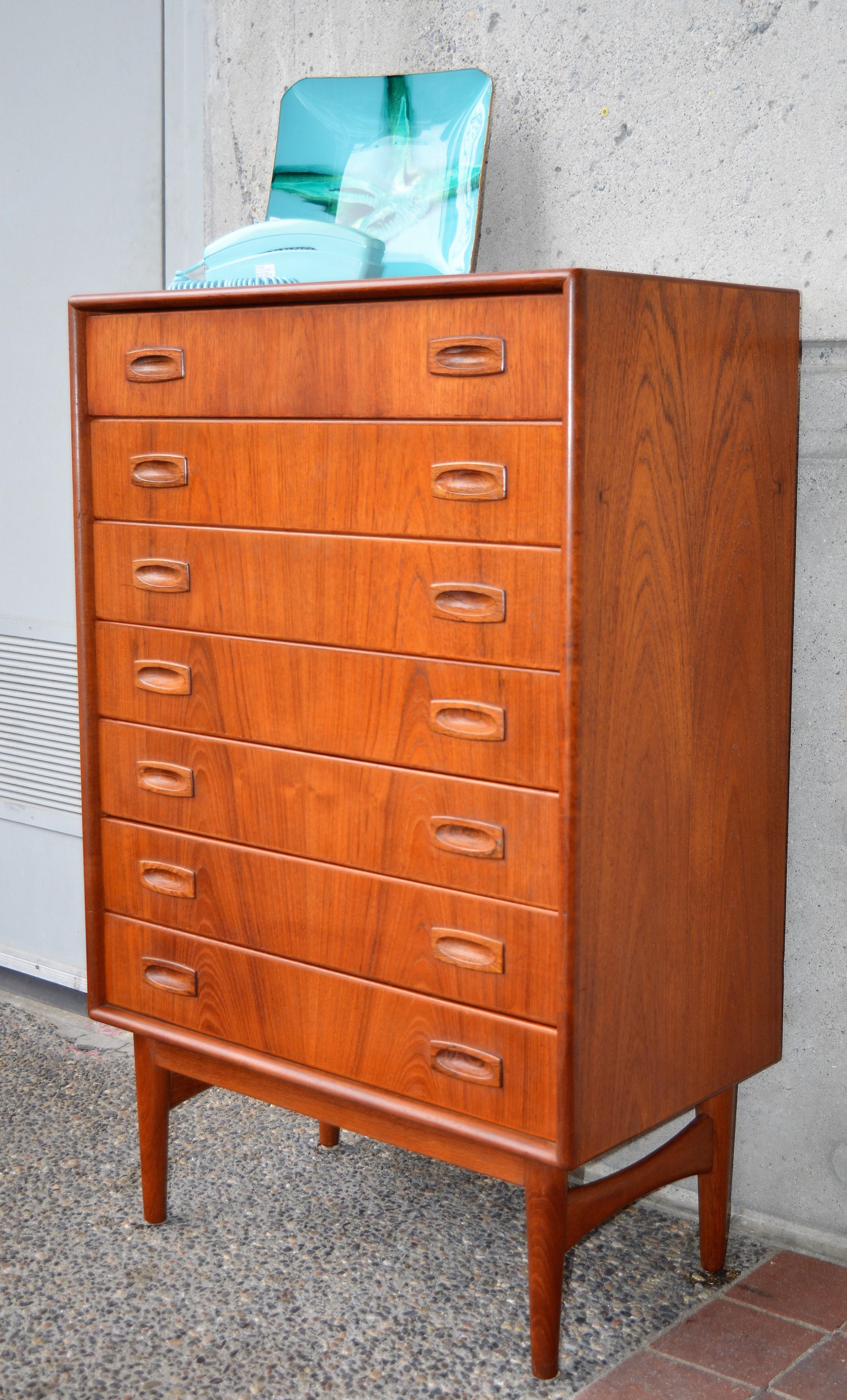 This Danish modern teak highboy dresser was designed by Arne Hovmand Olsen in the 1960s and is unusually narrow as well as with a shallow depth - so perfect for those with small spaces. Quality made with all wood construction, the 7 drawers have