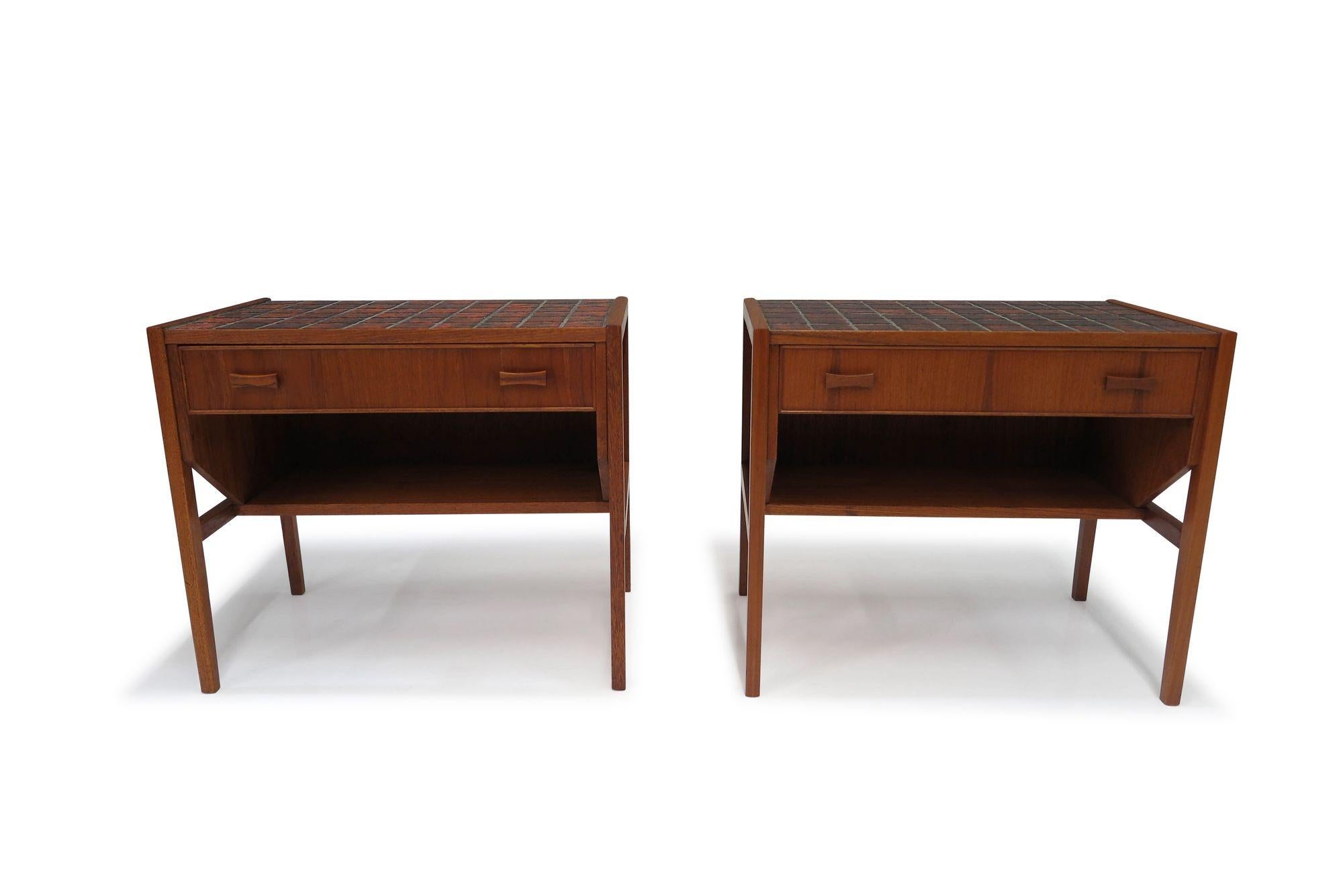 Pair of Scandinavian cabinets crafted from teak, featuring an orange ceramic tile top surface. Each cabinet has one drawer over an open storage space, raised on squared legs. The nightstands have been fully restored and are in good condition,