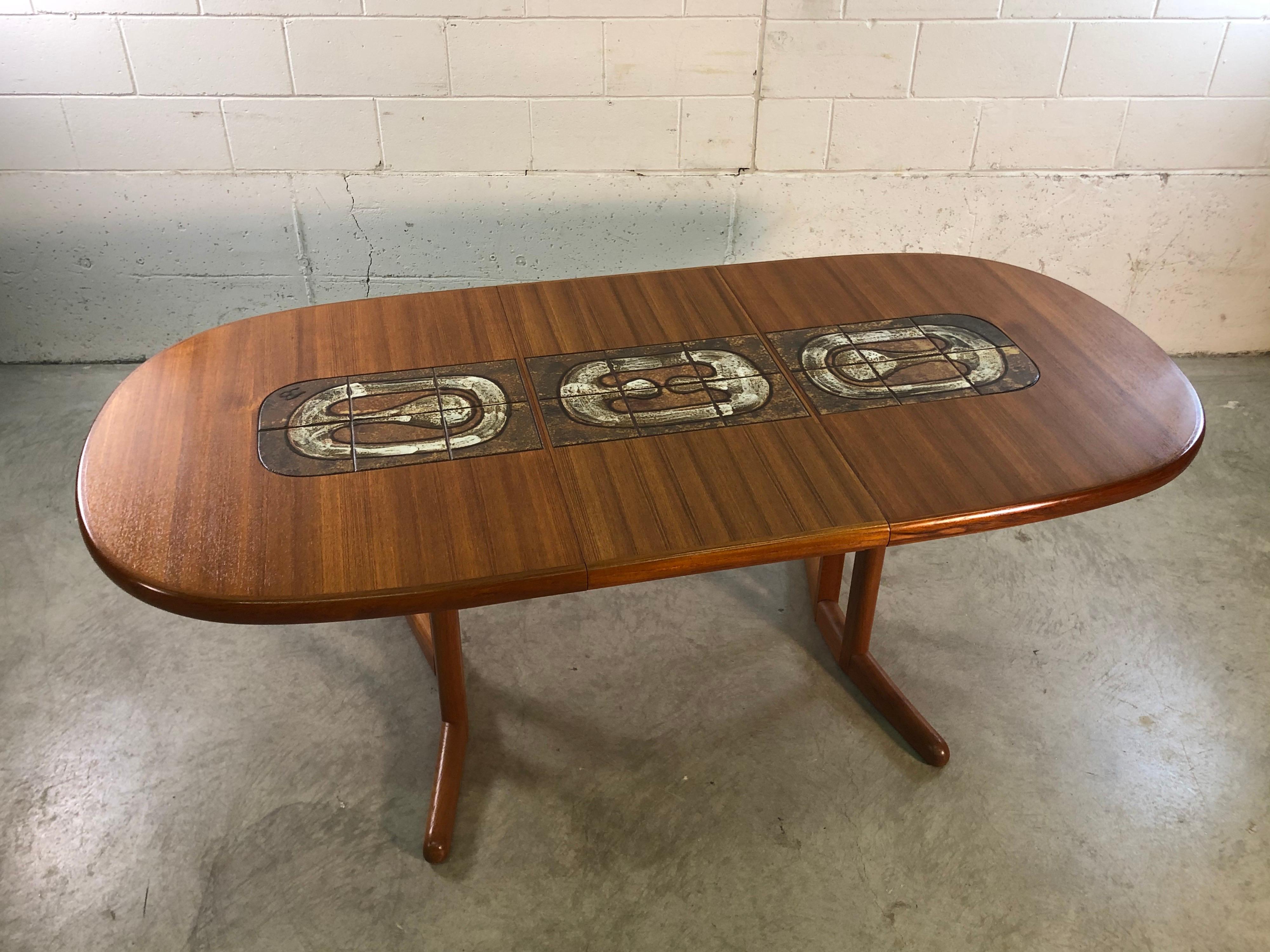 Vintage Danish modern oval teak dining table with tile top designed by AM Mobler. The tabletop tile is also included in the extra board. Table fully open is 78” W. Board is 19” W. Marked underneath.