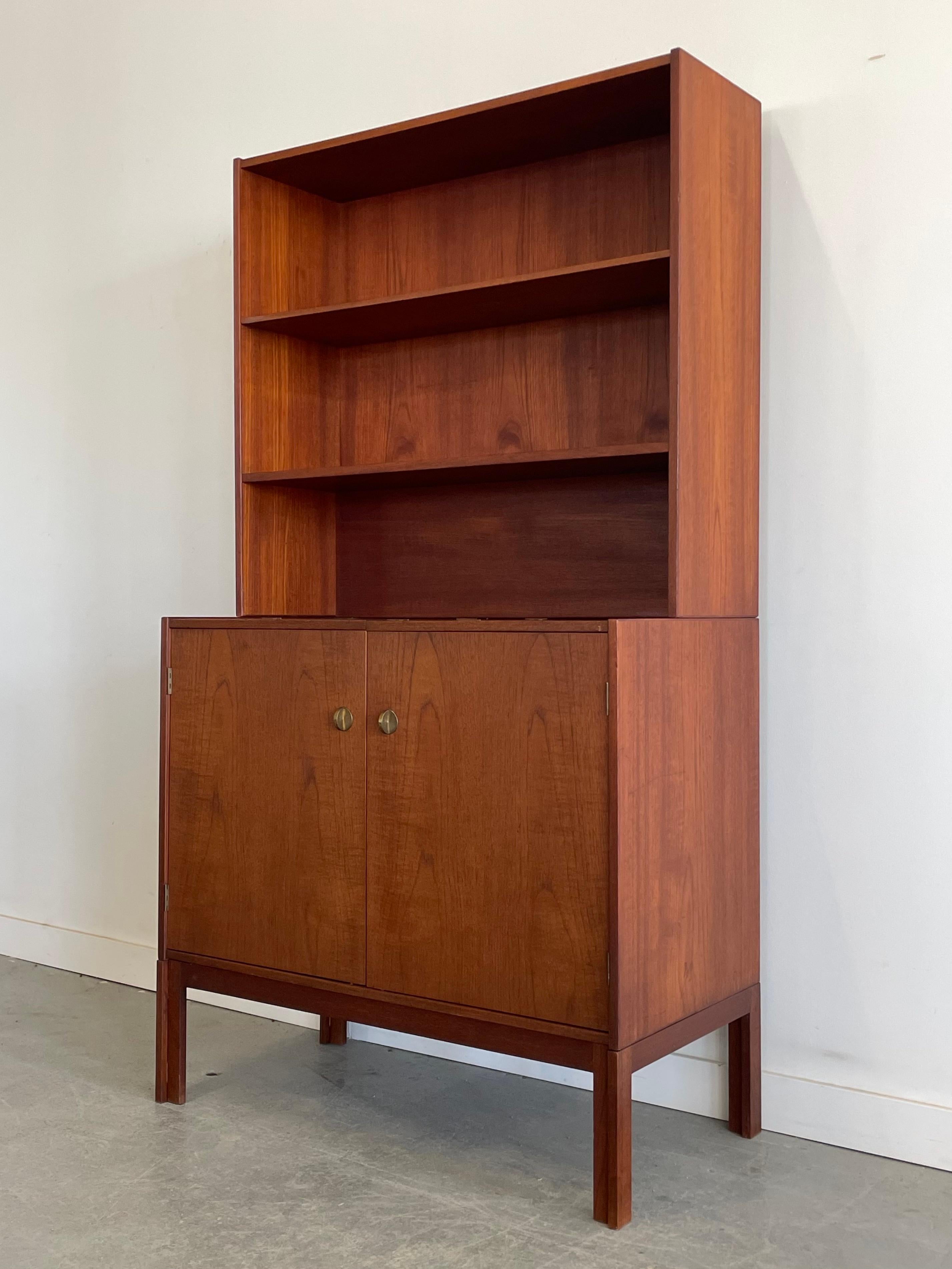 Versatile Danish teak record cabinet with shelf storage. This unique piece features solid construction, oak interior, mixed storage with venting, and beautiful cast brass detailing. This piece is by an unknown designer, but exhibits similar