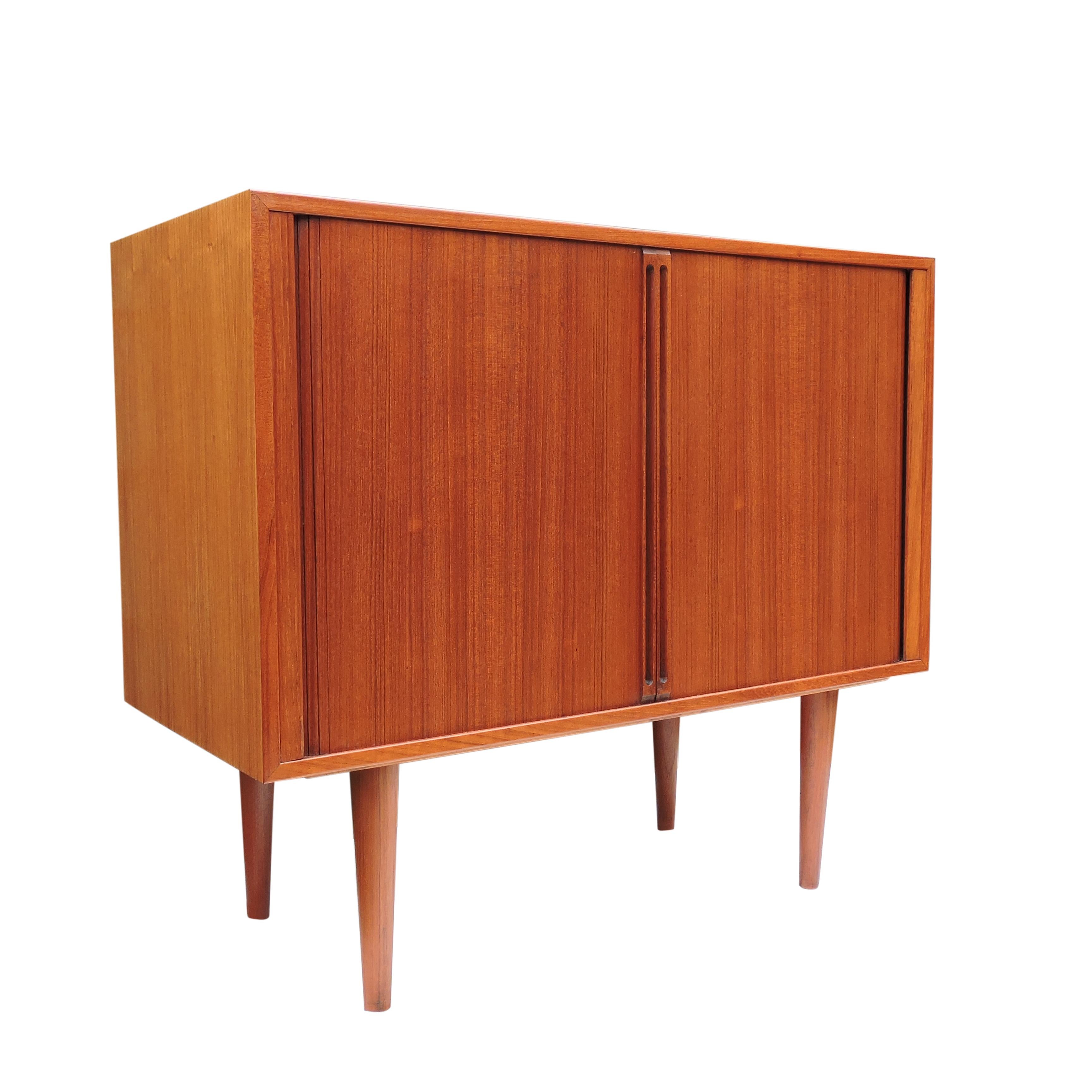 A teak tambour door record cabinet by Kai Kristiansen for Feldballes Mobelfabrik, Denmark, 1960s. There is divided space within, for records or books with two lower shelves.