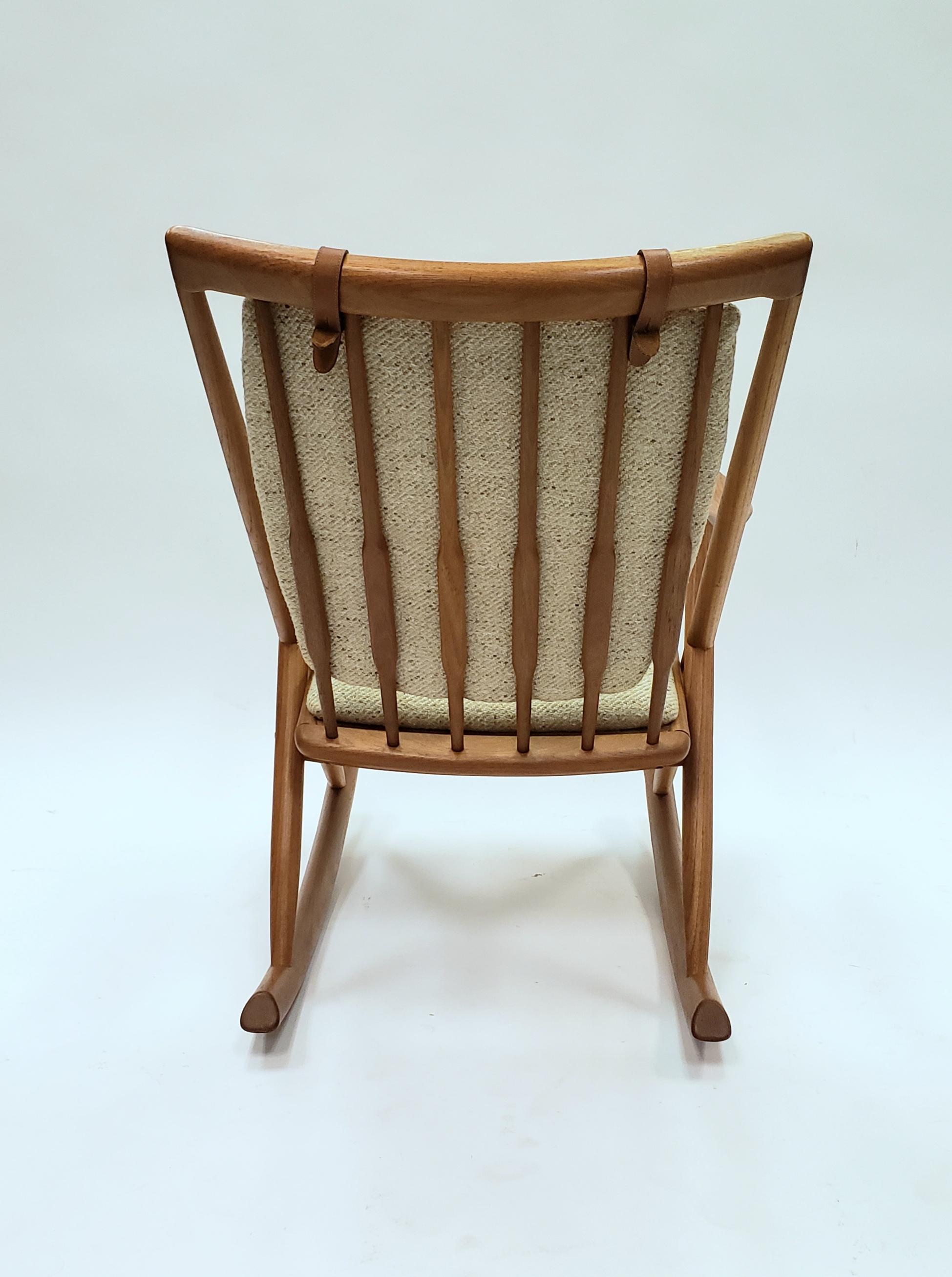 Lovely and comfortable Danish rocker made from teak. This rocker is attributed to Frank Reenskaug fir Brahmin but had no label. The wool seat is comfortable and attached with distinctive leather straps. The sculptural base gives it a distinct style.