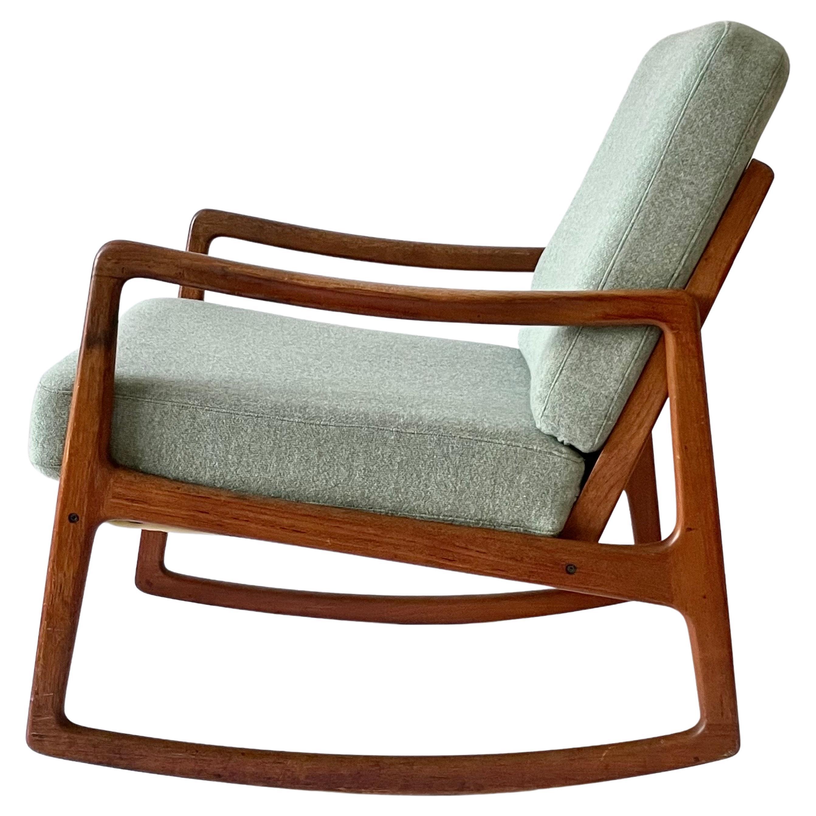 Rare mid-century rocking chair designed by Danish Professor Ole Wanscher. Made in Denmark by France & Søn during the 1950s. It maintains the manufacturer’s mark and features a sturdy teak wooden frame with a slated open back. The minimalist shape