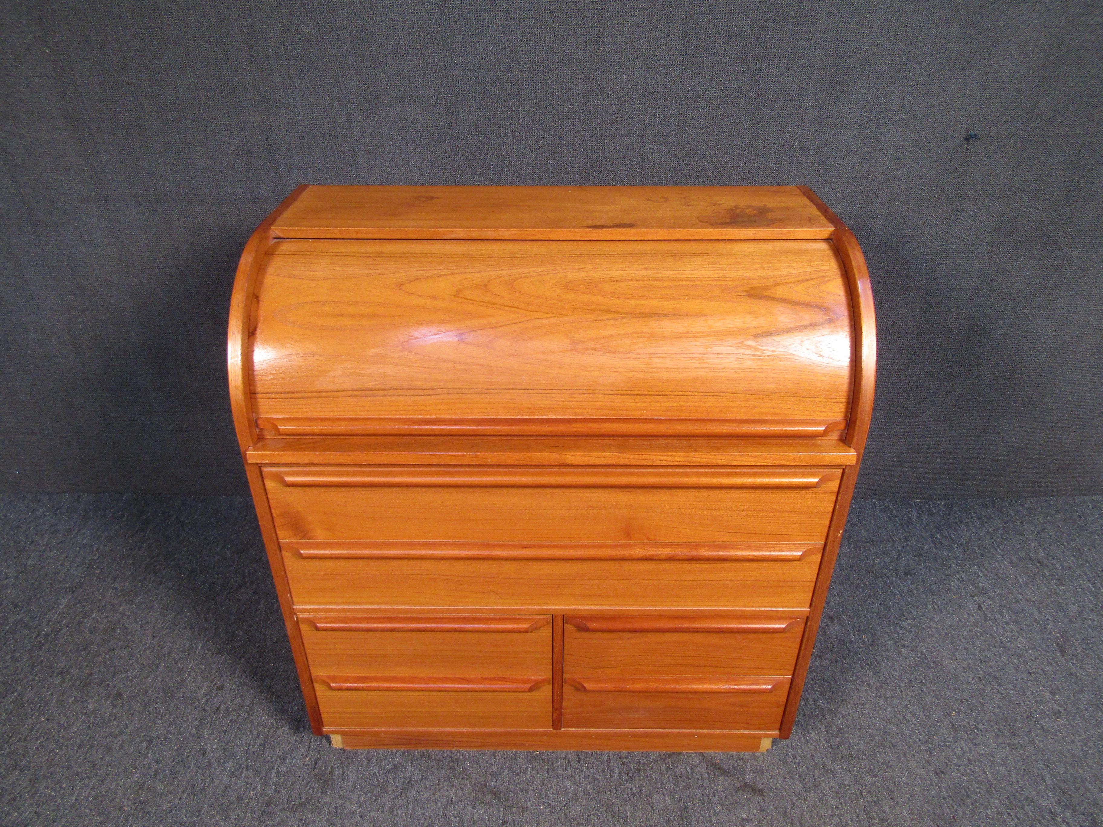 With an interesting compact shape and plenty of storage, this Mid-Century Modern rolltop desk is unique in size and design. A large amount of drawer space allows this vintage piece to be used in multiple ways. Please confirm item location with