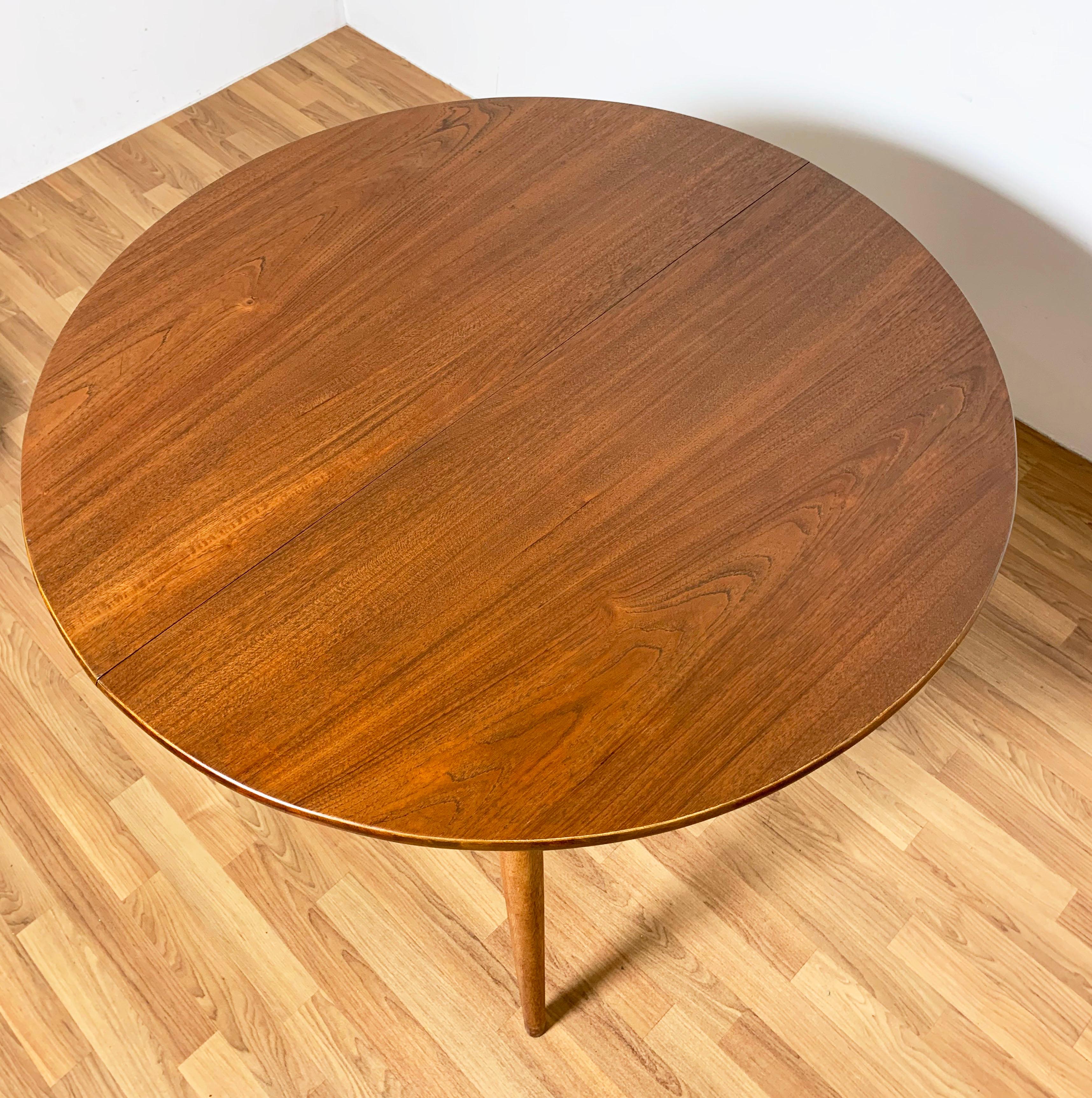 Danish teak circular dining table with a gracefully arched skirt, with two skirted 12