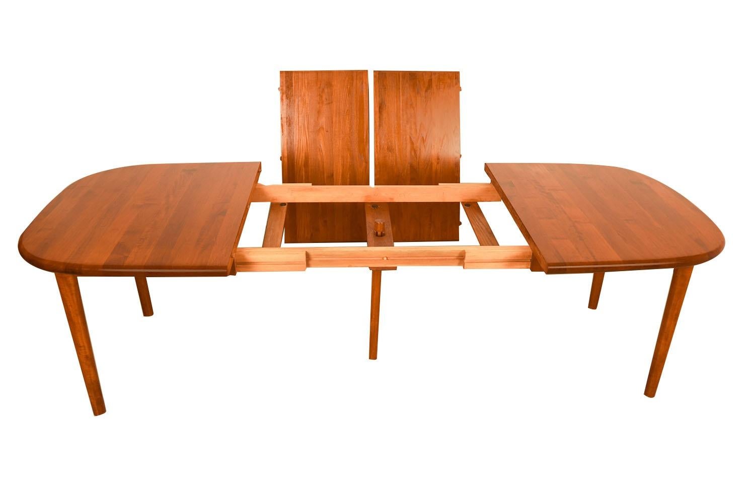 Beautiful Mid-Century Modern teak rounded corners rectangle expandable dining table, circa 1970’s. Featuring richly grained, gleaming teak and smooth, clean lines characteristic of classic Danish design. This remarkable dining table comes with two
