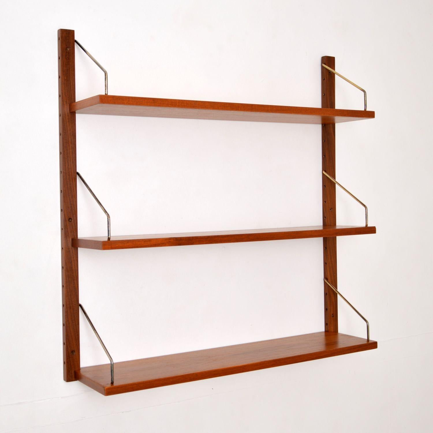 A stylish and top quality vintage Danish teak bookshelf. This was designed by Poul Cadovious and was made by Cado in the 1960s-1970s.

This comes with two wall mounting rails, and three shelves with brass supports. In addition there is a fourth