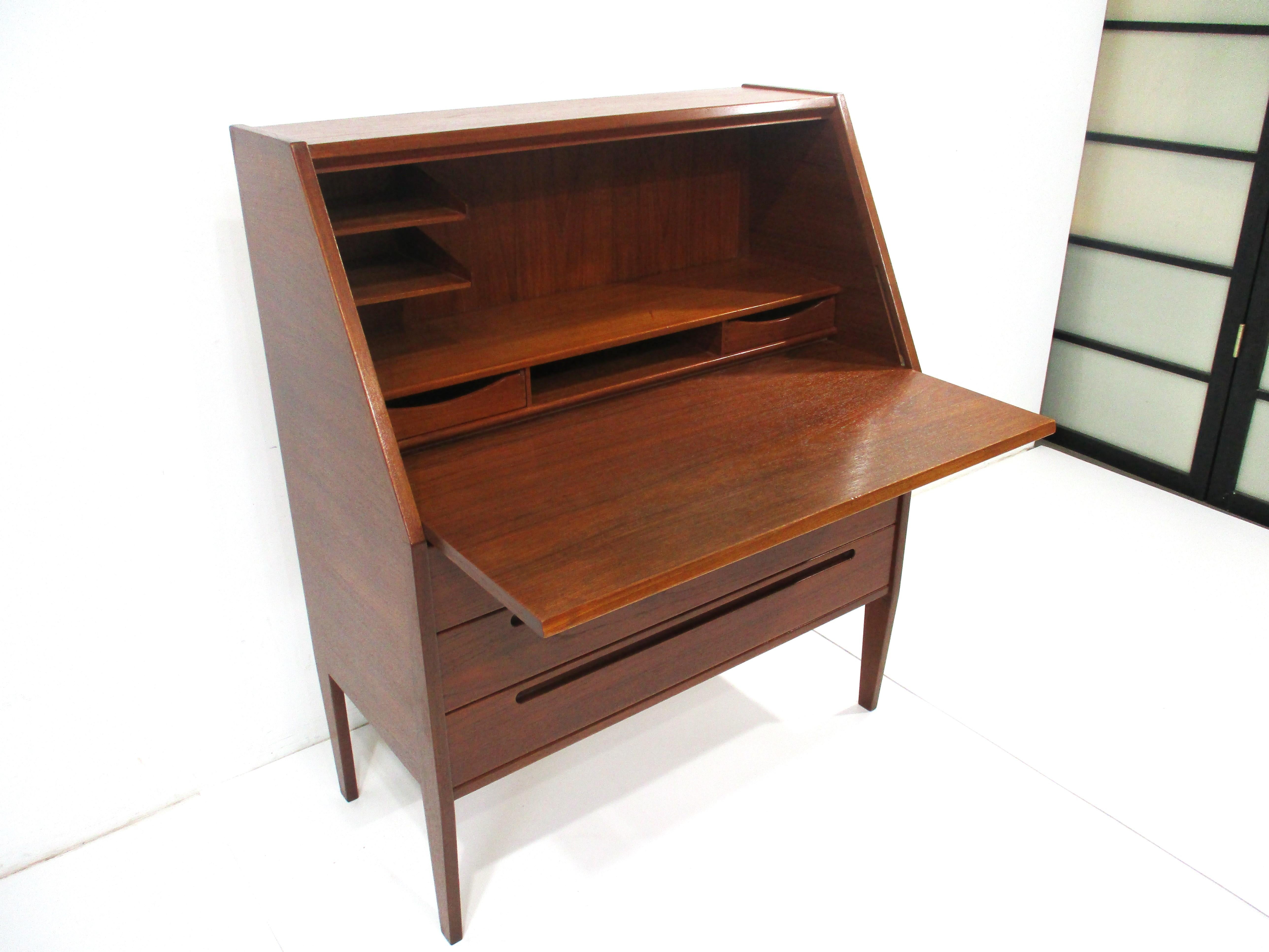 A very well crafted dark teak wood secretaire with pull down door front that slides back to make an adjustable desk top . Inside there is great storage with two floating letter holders , two small drawers an open compartment and shelve . The lower