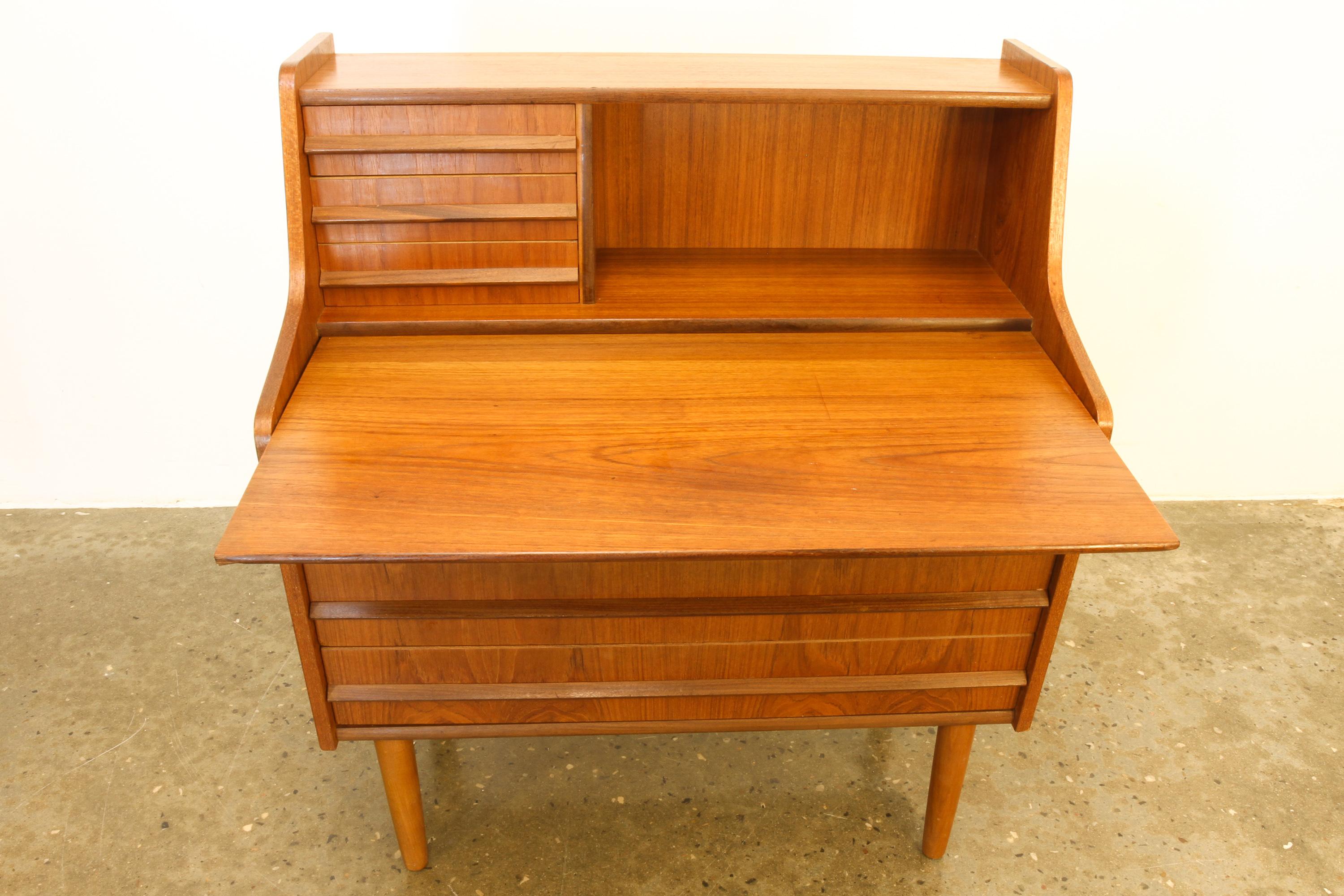 Danish teak secretary, 1960s.
Classic Danish midcentury modern secretaire/bureau with drawers.
Features a draw out table top, three large drawers, three small drawers and open compartment.
Drawers has long sculpted grips in solid teak. Standing