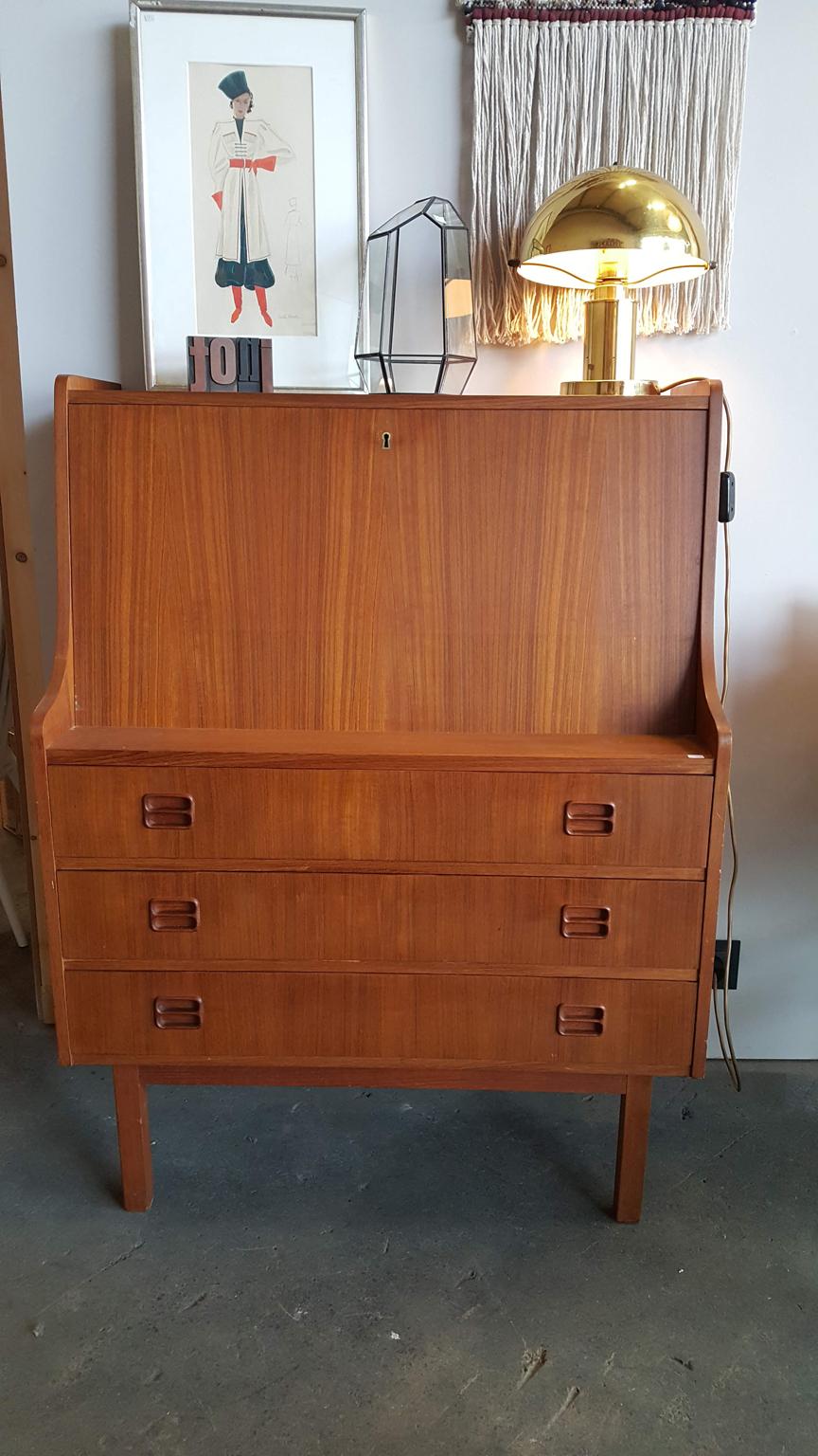 Nice little secretary from Denmark. Square body with a flap and three skirts. Flap lockable, key missing. Behind the flap there are compartments and 2 slippers. The body of the secretary is made of wood with teak veneer, the small drawers hunter the
