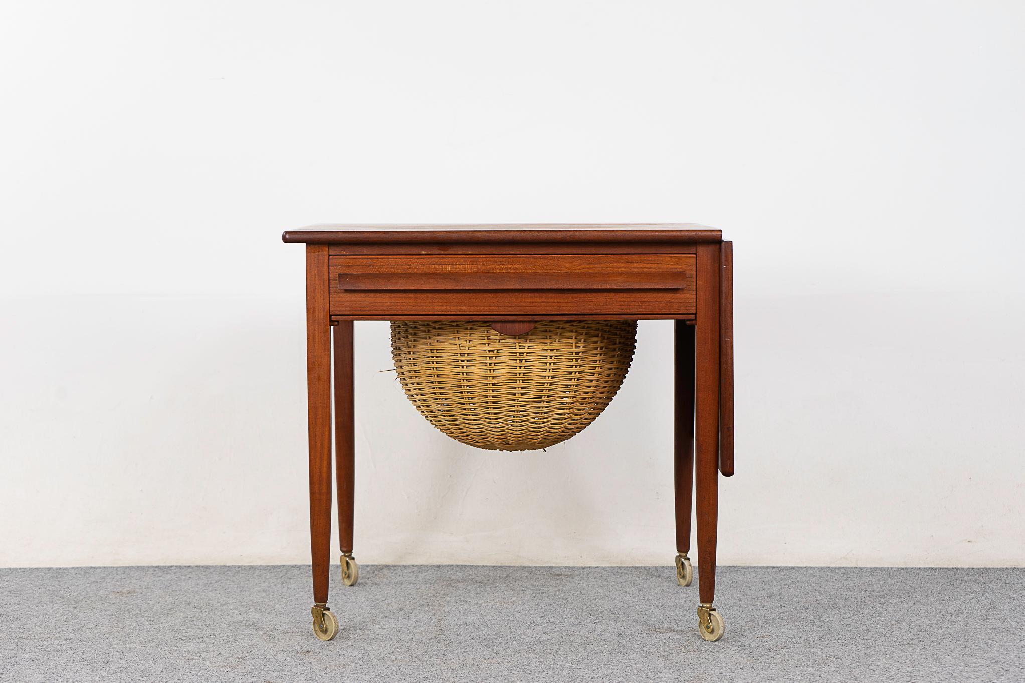 Teak sewing table by Johannes Andersen, circa 1960's.  Designed as a sewing table, this piece offers versatility that goes beyond the sewing room! Perfect as an end table or accent piece. Handy drawer with fitted interior, original woven basket