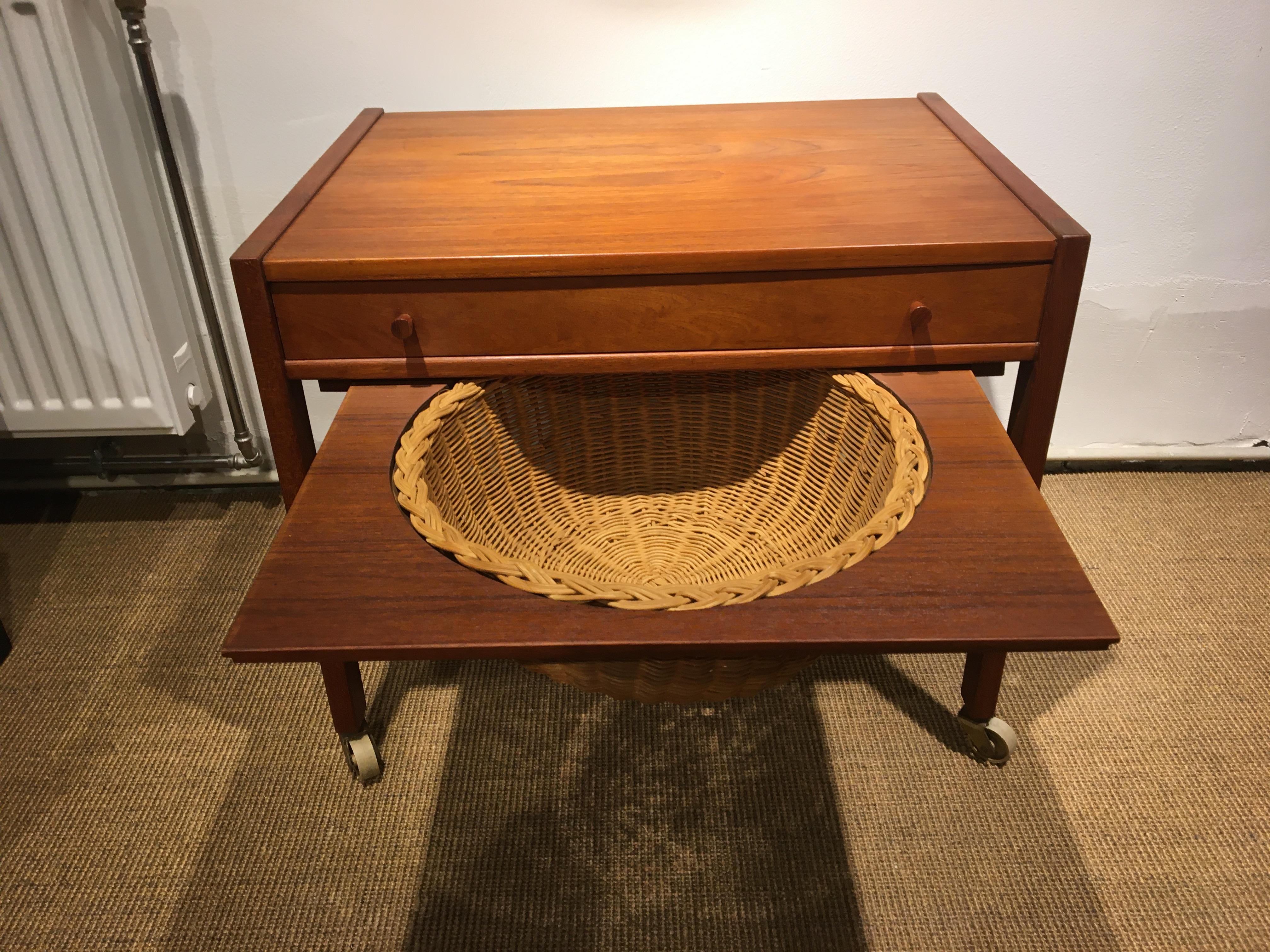 Small teak sewing table with 2 small fine twist grips.
Dividing into drawers for the handicraft.
And a nice rattan knitting basket underneath.
Features original brass wheels with white rubber coating.
Can be used as a small coffee table, as the