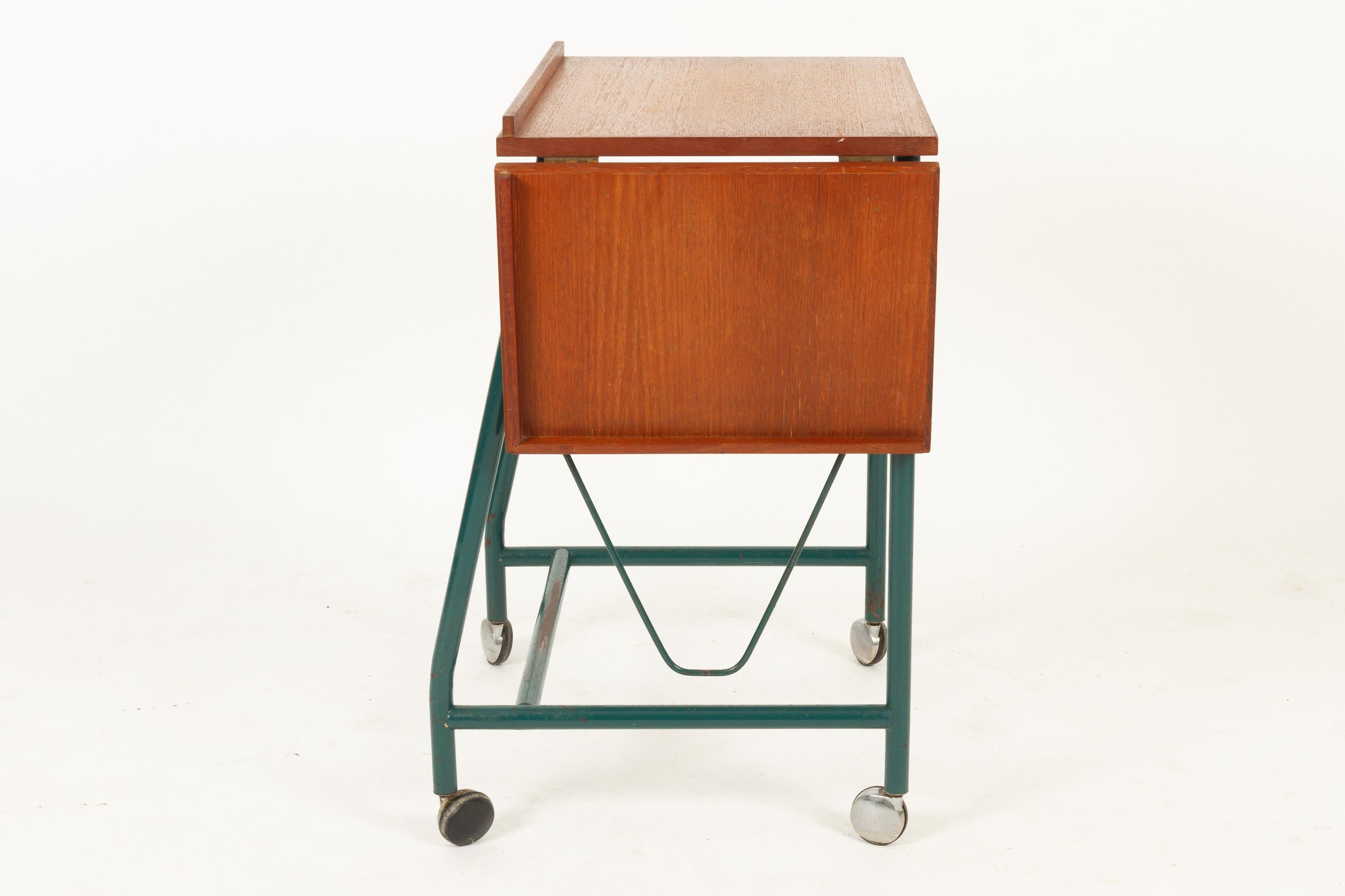 Danish teak side table with green metal frame, 1960s

Vintage Danish trolley with teak tabletop, green metal frame on wheels. Table has a hinged extension blade. Originally probably used as a typewriter desk.
Versatile piece of Mid-Century Modern