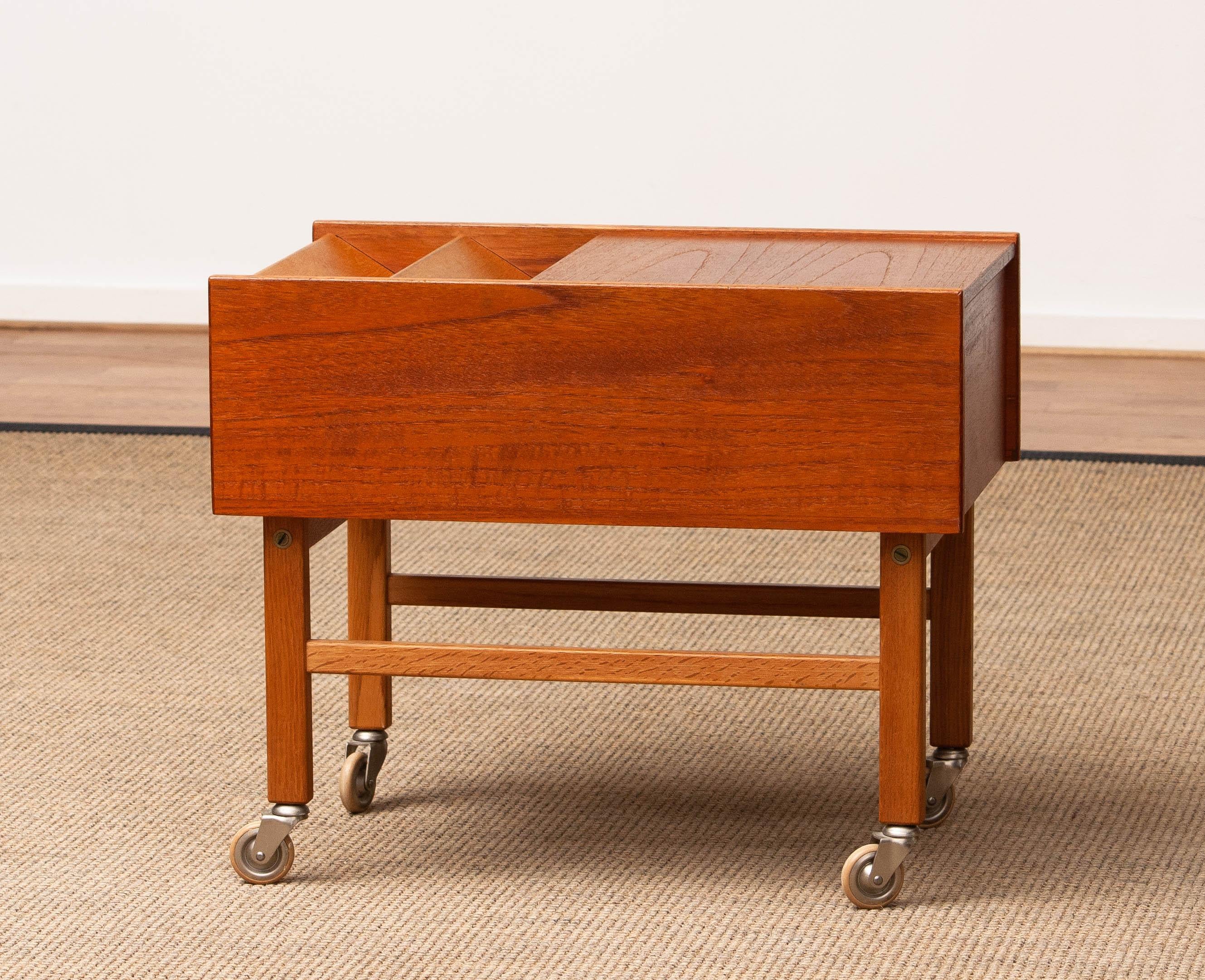 Tavolino in teak della metà del secolo scorso proveniente dalla Danimarca, risalente agli anni '60, dotato di pratici scomparti per riporre riviste e giornali. Il design include un pannello scorrevole che rivela una piccola sezione per riporre i