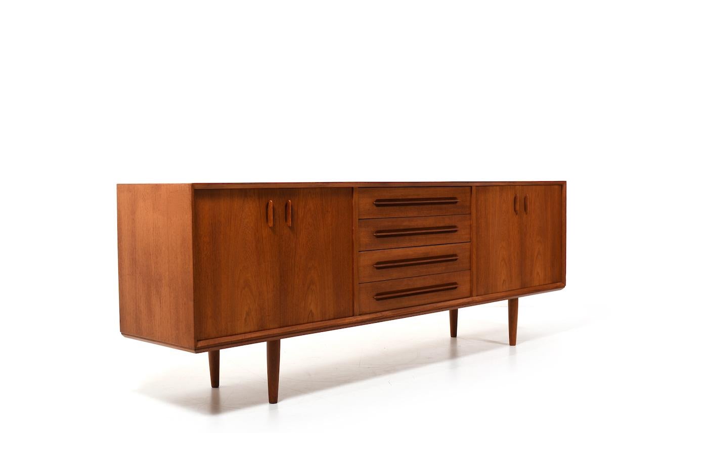 Beautiful danish teak sideboard by Ejvind A. Johansson for Gern Møbelfabrik Denmark 1960s. In front with double doors on each side and shelves behind them. In the middle a row of drawers. With beautifully crafted handles. In very good quality. In