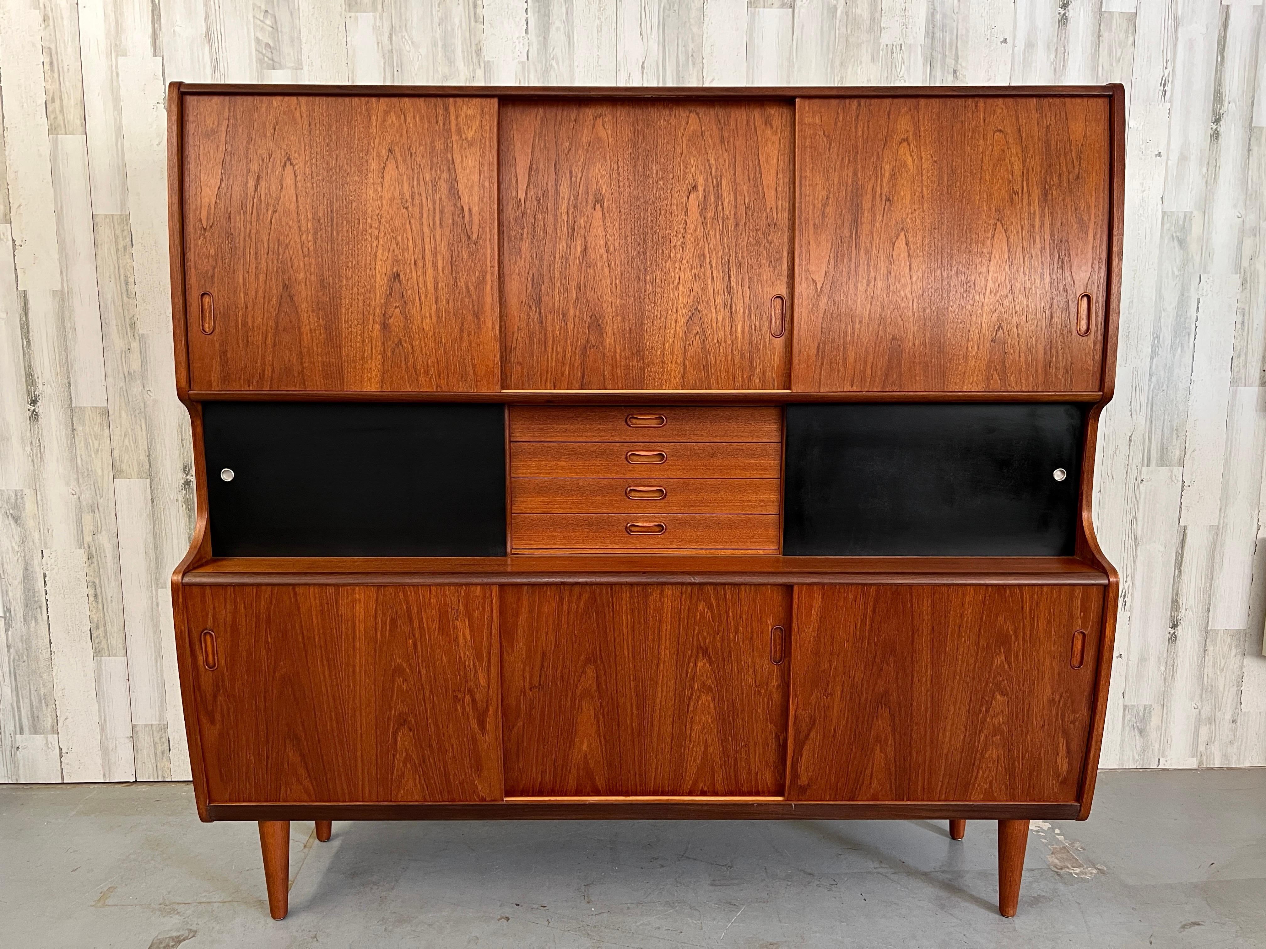 Sculpted teak highboard / credenza with mirrored center cabinet and masonite sliding doors.
Lots of storage or use as a bar.
