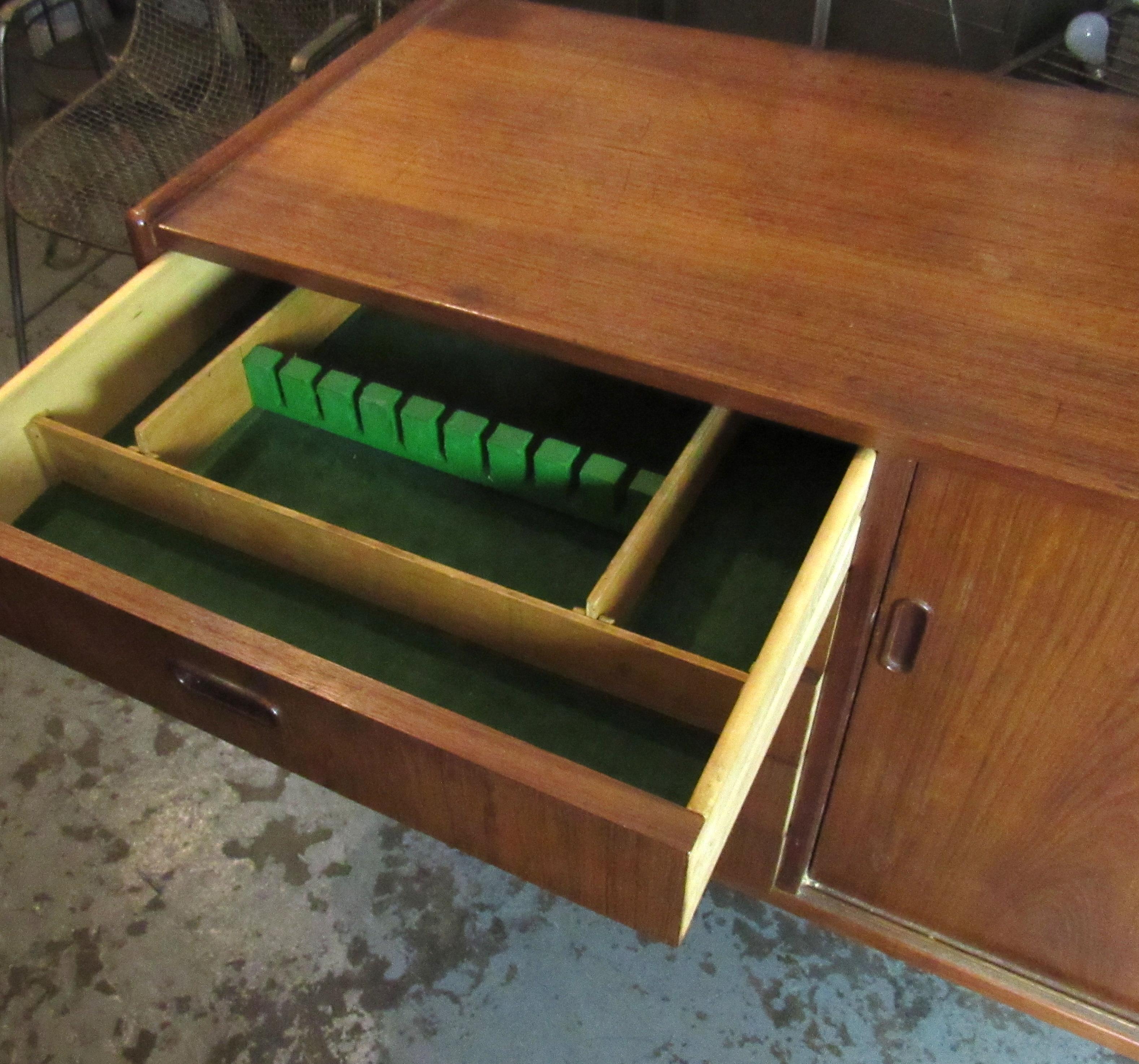 Vintage modern cabinet with sliding door storage and five side drawers. Warm teak grain, sculpted handles and tapered legs.
(Please confirm item location - NY or NJ - with dealer).
 