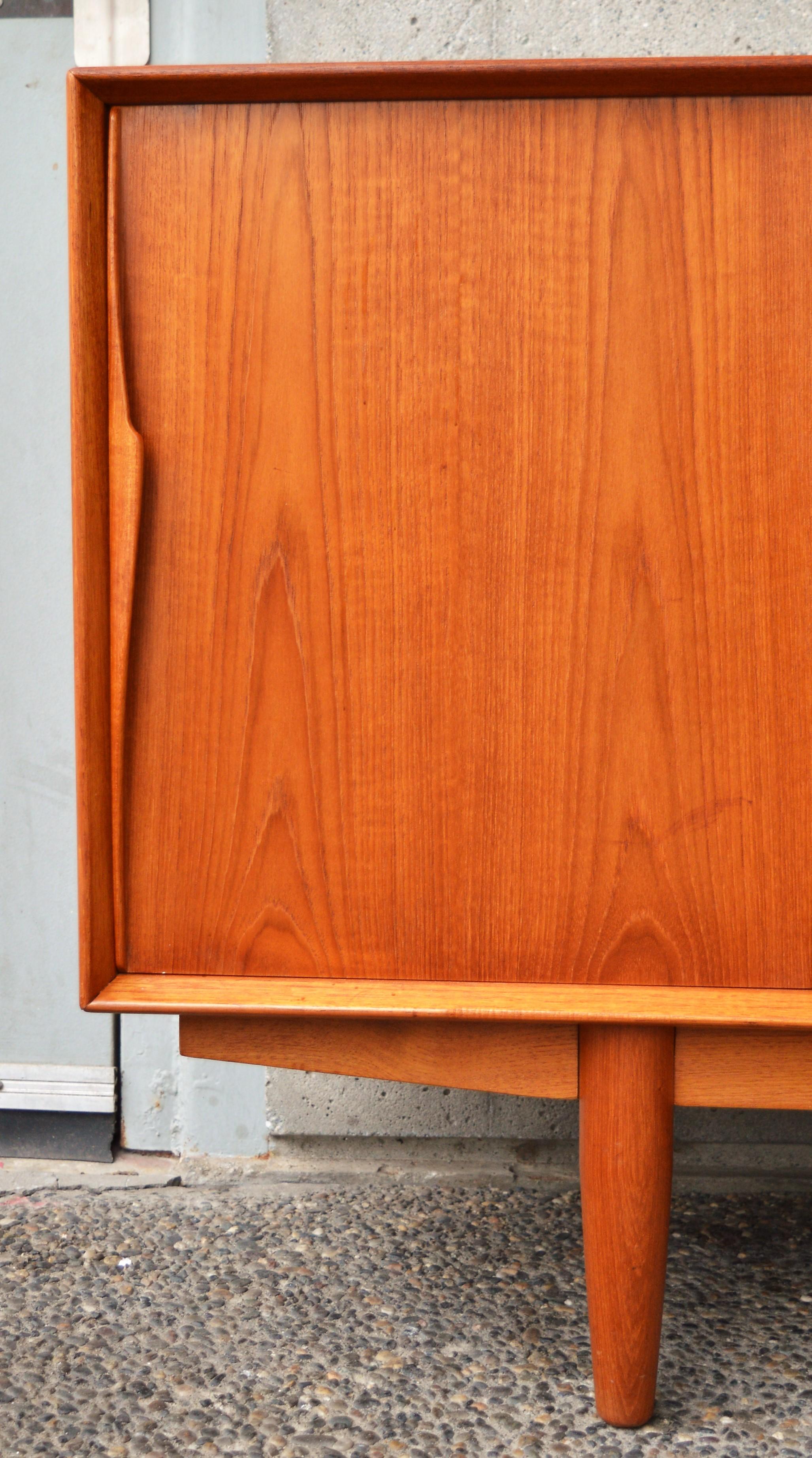 This impeccable Danish modern teak buffet is exquisite throughout and was inspired by Arne Vodder for Dyrlund. Featuring a center bank of bow-tie shaped drawers, with all hardwood construction and dovetail joins (the top two are slimmer and felt