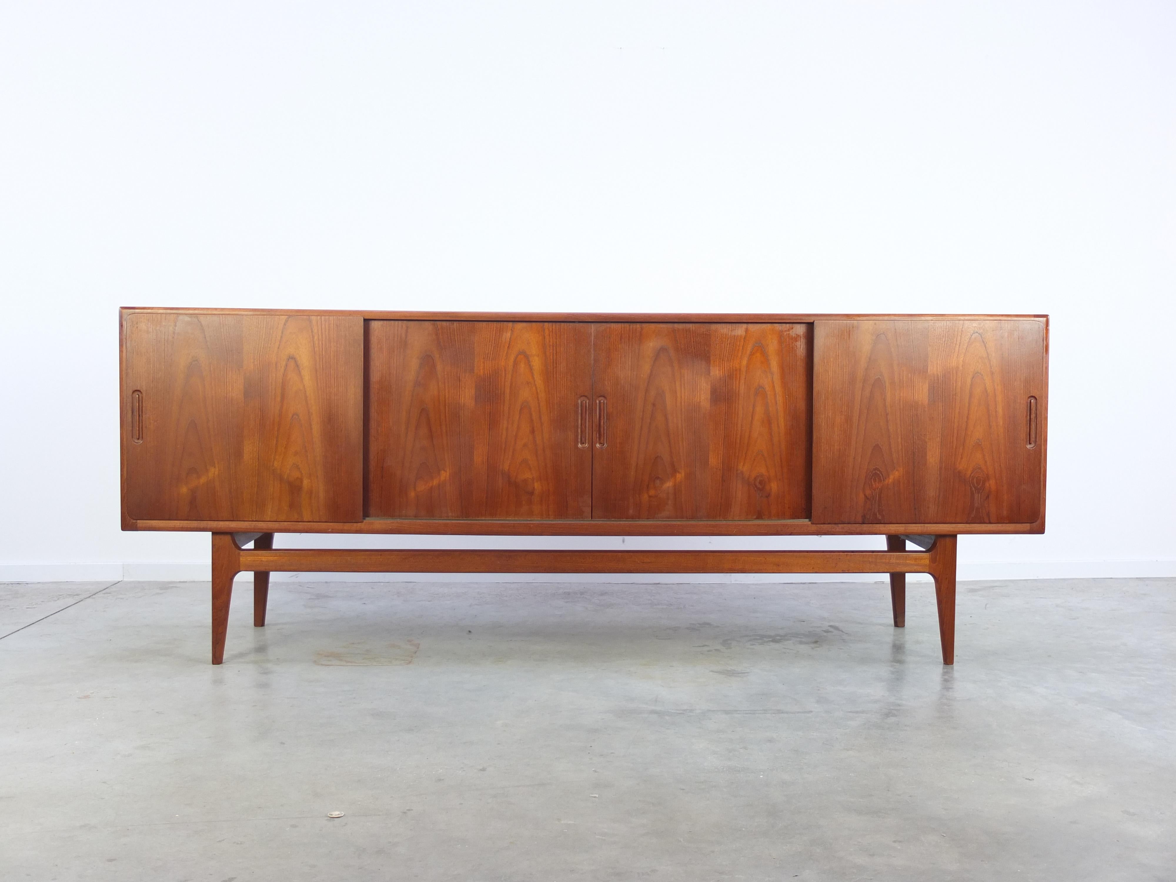 Elegant teak sideboard produced by Bernhard Pedersen & Søn in Denmark during the 1960s. This sideboard is made of teak wood with a beautiful woodgrain and features 4 sliding doors. Behind you can find shelving space and 4 drawers. A very nice detail