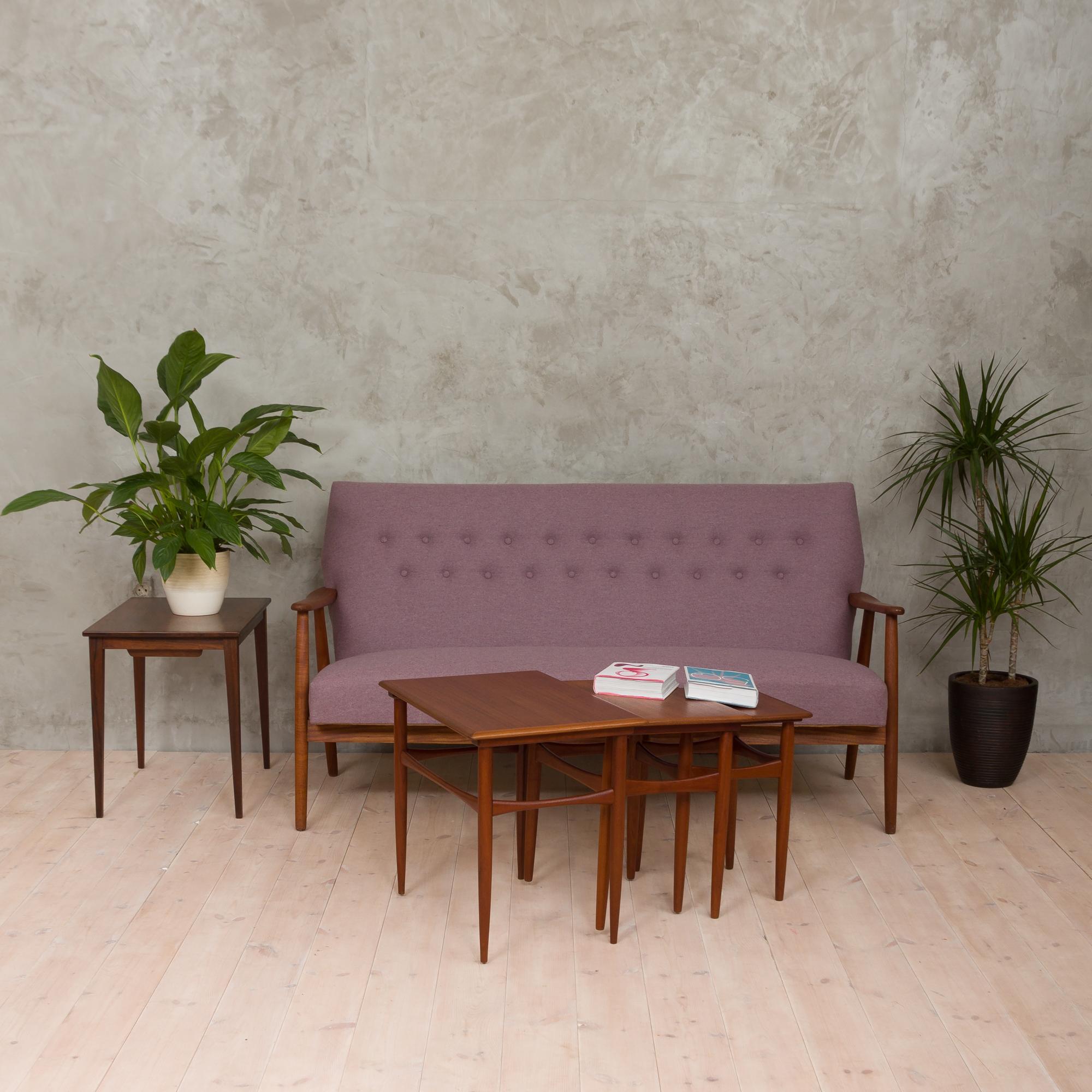 Danish midcentury sofa that features a frame in solid teak and was reupholstered in a light lilac natural wool fabric. It has a coil spring seat and was restored using traditional techniques according to the original design of the piece. The sofa is