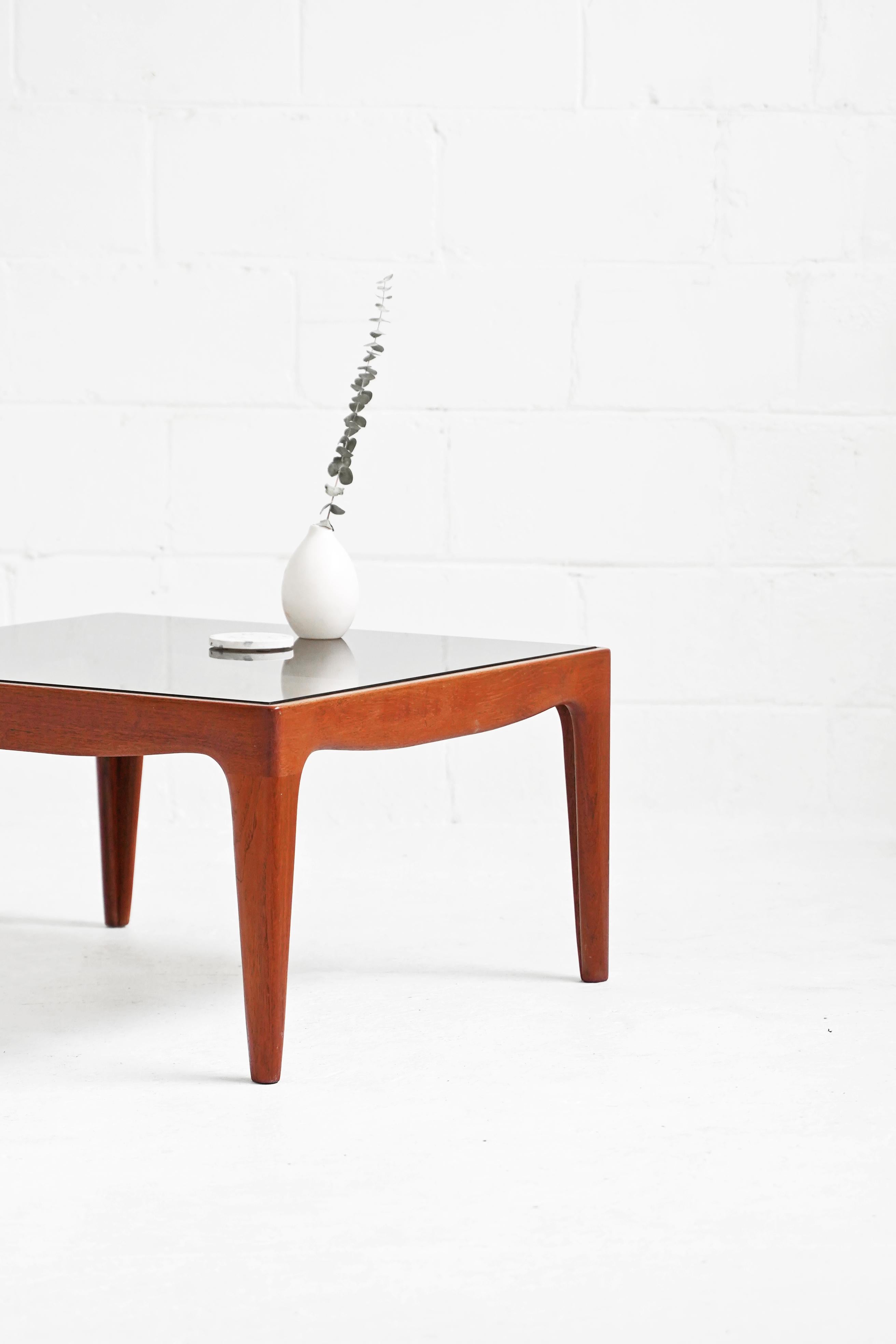 Stunning coffee table in teak and smoked glass. Faint scratching on glass top, but overall in great vintage condition.

Measurements:
Rectangular 61 1/2