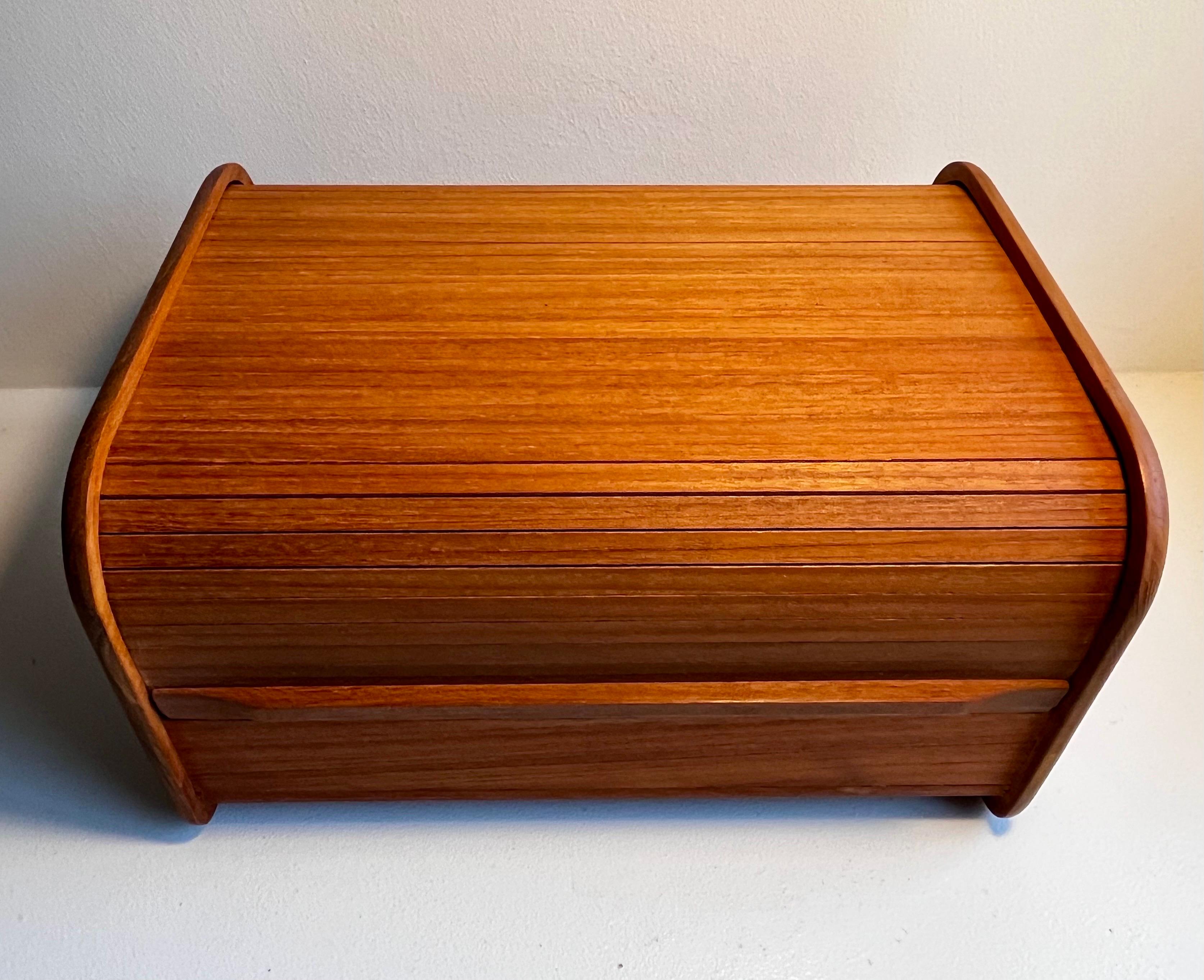 Caja de almacenaje de teca con puertas de persiana
hacia 1970

Una puerta corredera de persiana.
Tres zonas de almacenamiento en el interior.


