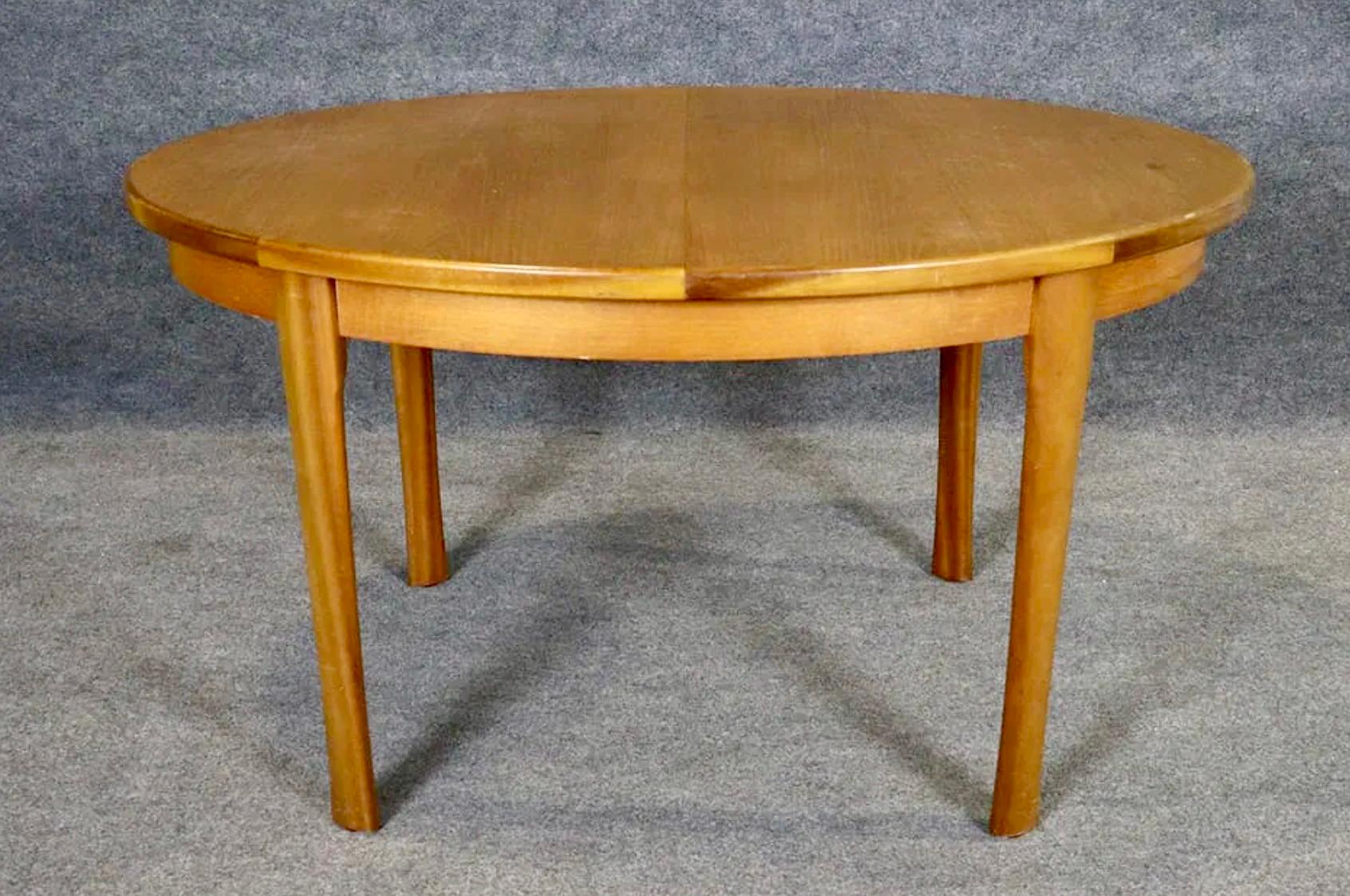 Table de salle à manger ovale en bois de teck au grain chaud. Comprend une feuille papillon qui permet d'ouvrir la table de 53