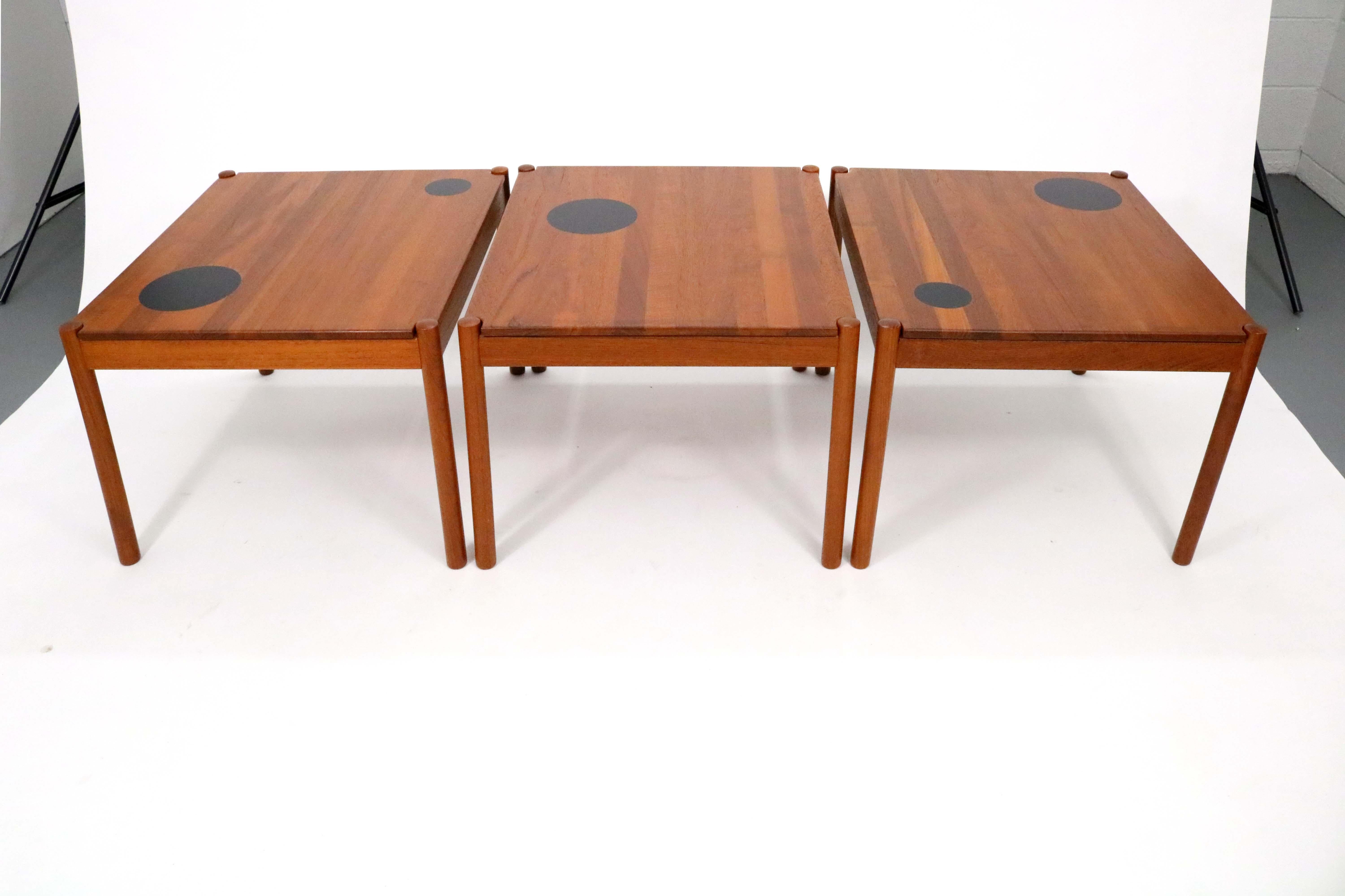 A trio of solid teak vintage mid-century Danish side tables with black faux leather applique 