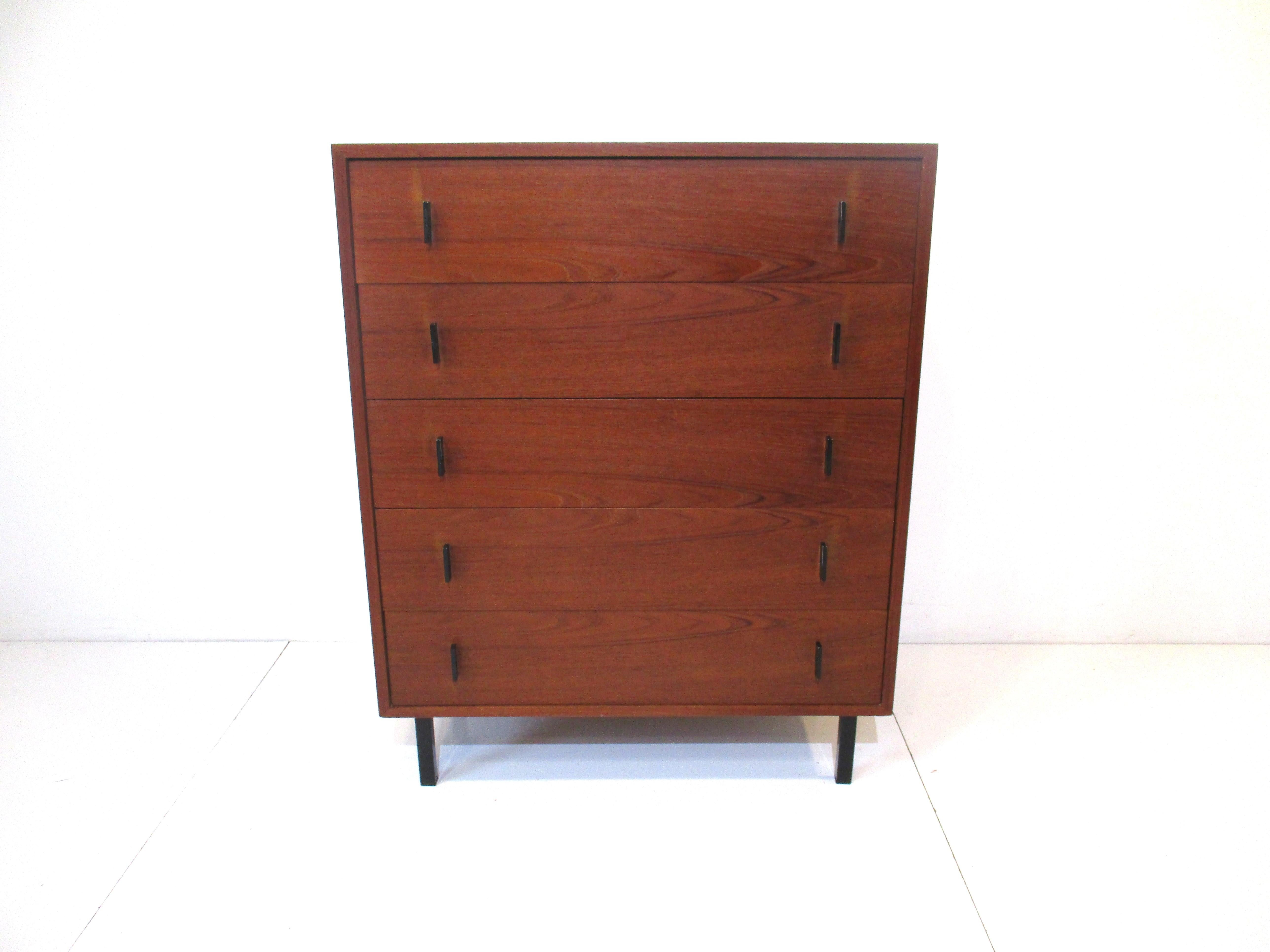 A very well crafted medium dark teak wood tall dresser chest with satin black metal pulls and legs. The pulls have a nice hole design giving the piece more detail, having plenty of storage and style in the manner of Arne Jacobsen.