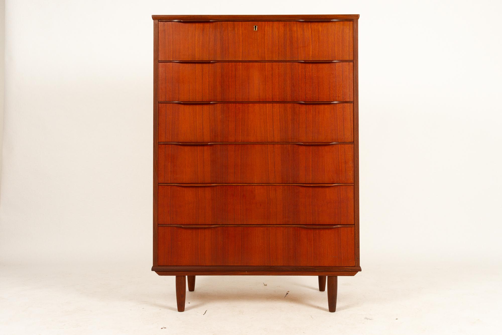 Danish teak tallboy dresser, 1960s.
Mid-Century Modern tall chest of drawers in teak veneer with six large drawers with sculpted handles in solid teak. Round tapered legs in solid teak.
Good original vintage condition. Lock is defect, please see