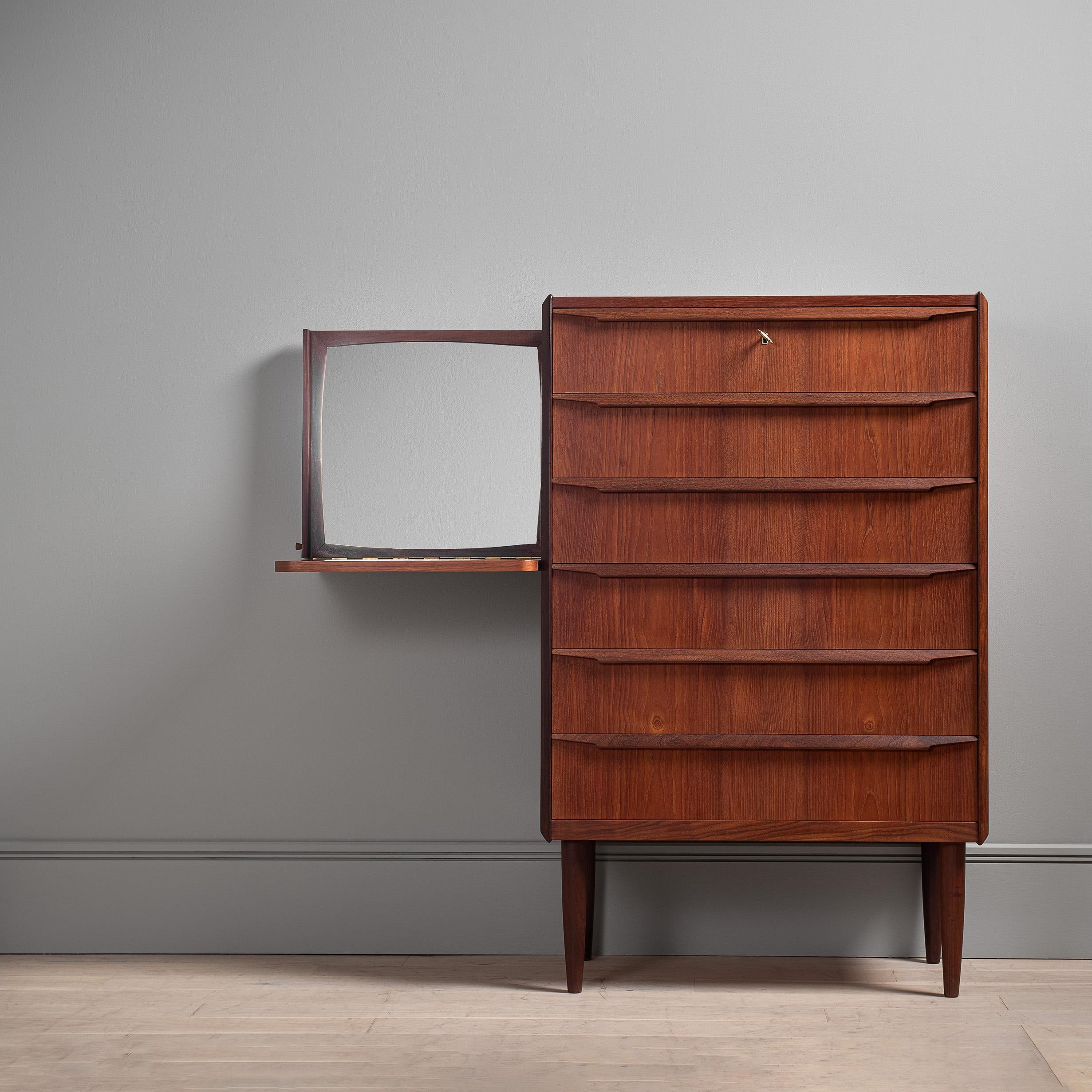 Un meuble au design scandinave incroyablement inhabituel. Tallboy en teck danois avec un meuble-lavabo coulissant/caché et un miroir. La partie vanité est accessible d'un côté et glisse lorsqu'elle n'est pas utilisée. Le tiroir supérieur se ferme