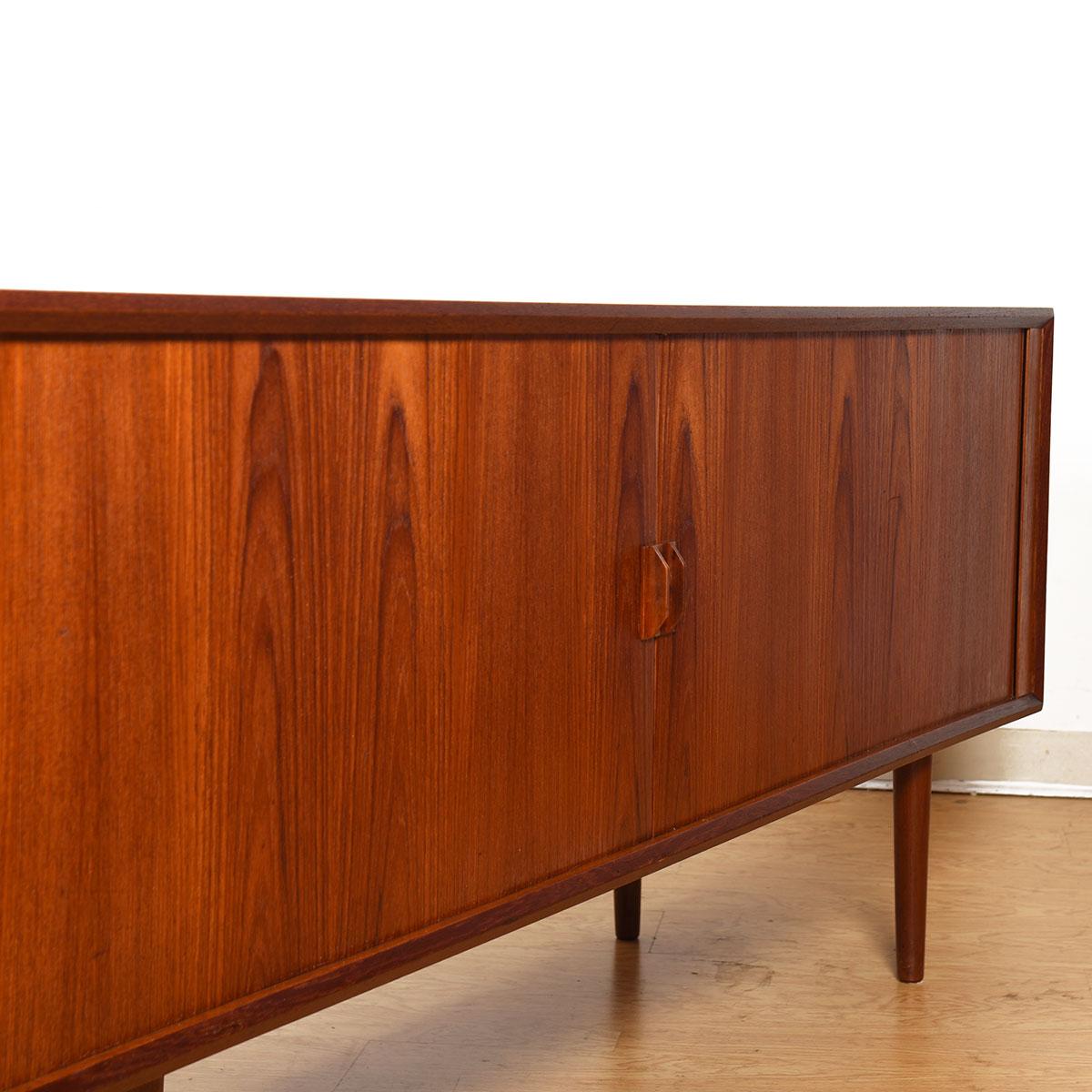 A Danish modern teak sideboard / room divider. Featuring tambour doors that slide open to reveal four felt lined drawers & two adjustable shelves.
The backside is fully finished, allowing it to be placed in the middle of a room.