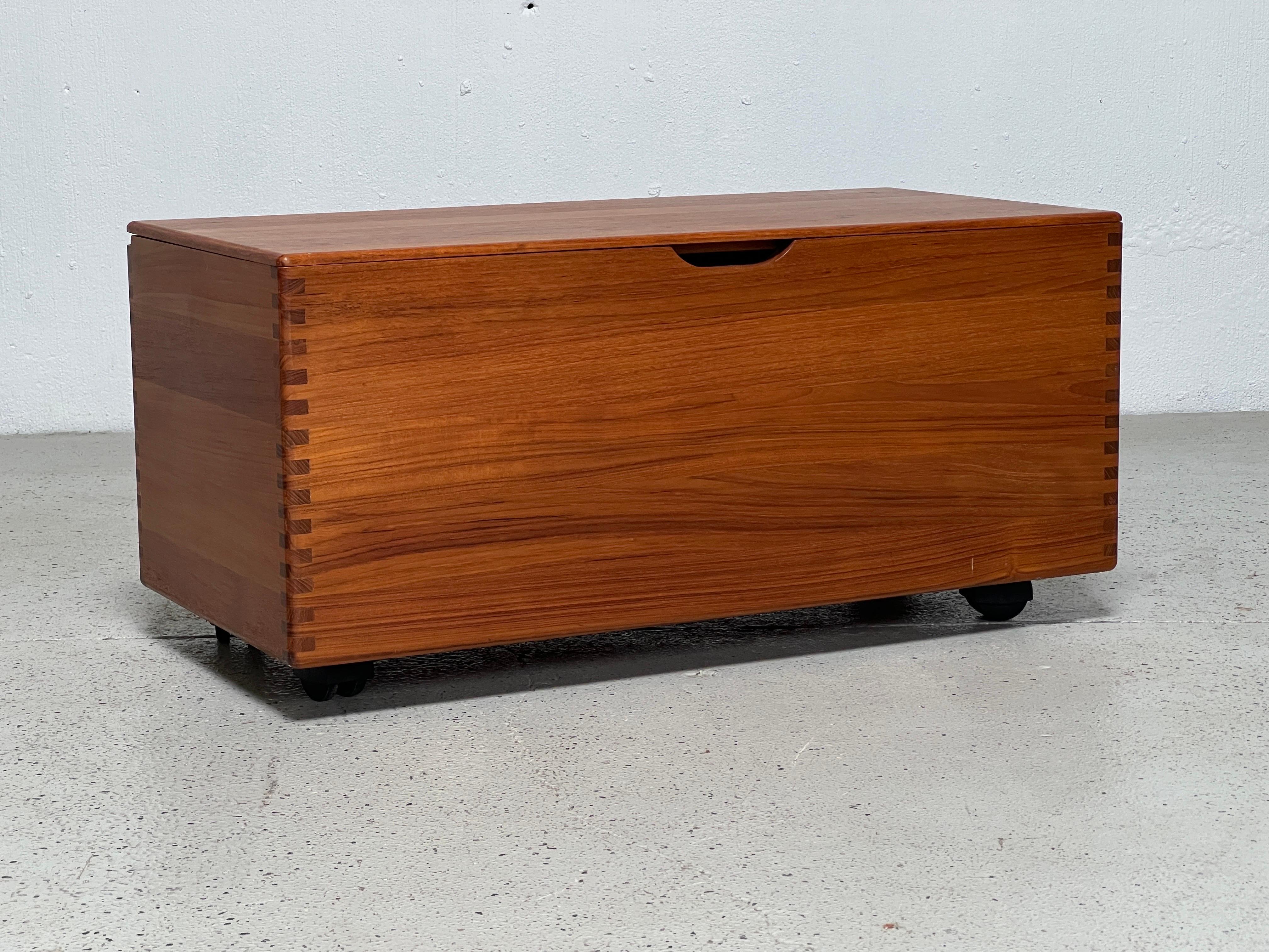 A teak trunk on casters with exposed finger joints, wooden hinges and a removable trey. Marked made in Denmark. 