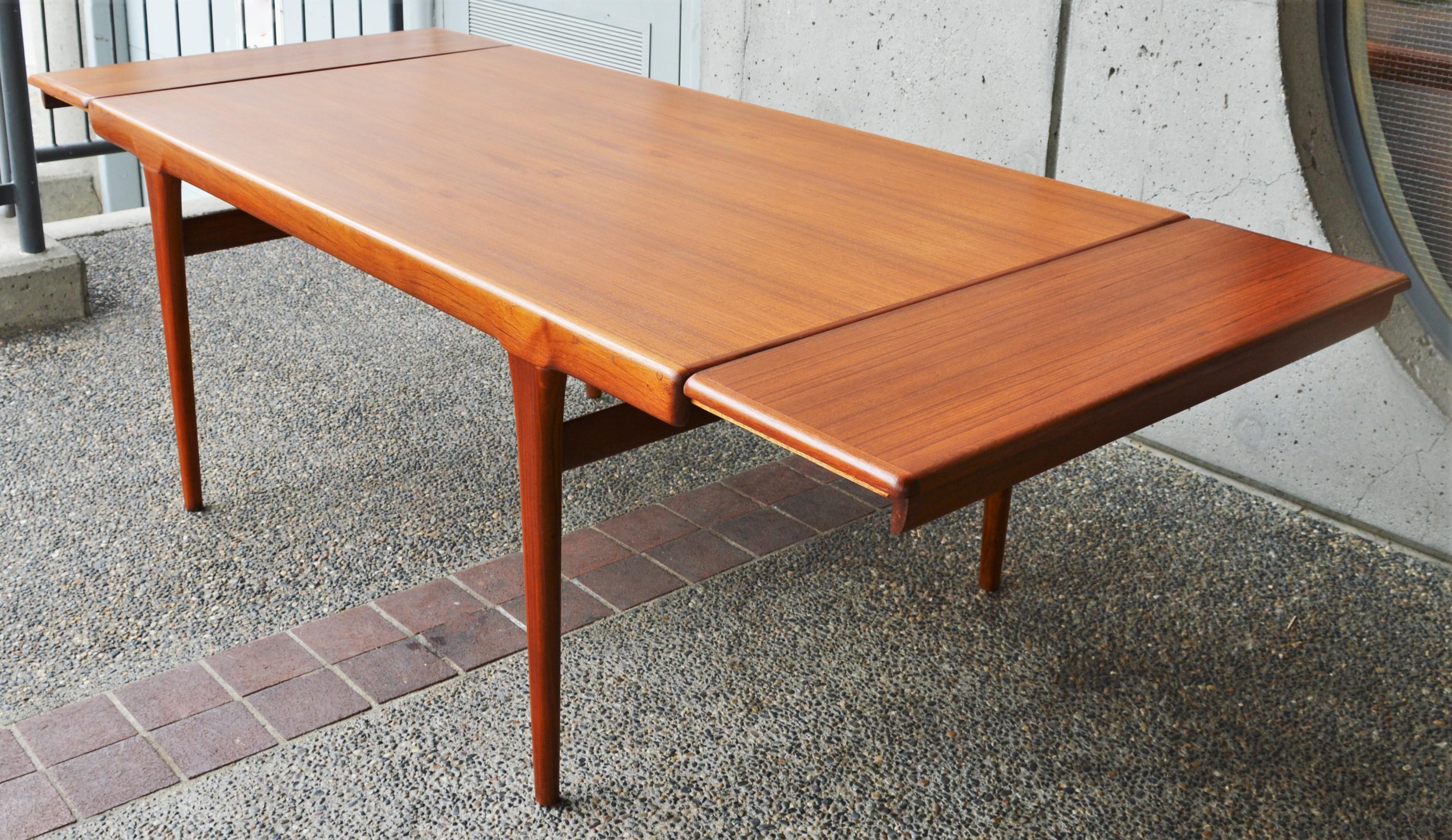 This stunning quality Danish modern teak dining table was designed by Ib Kofod Larsen in the 1960s. Note the sultry thick top edge that contours to flare into the sword blade legs, the curved ends, the ovoid cross braces between the legs, and the