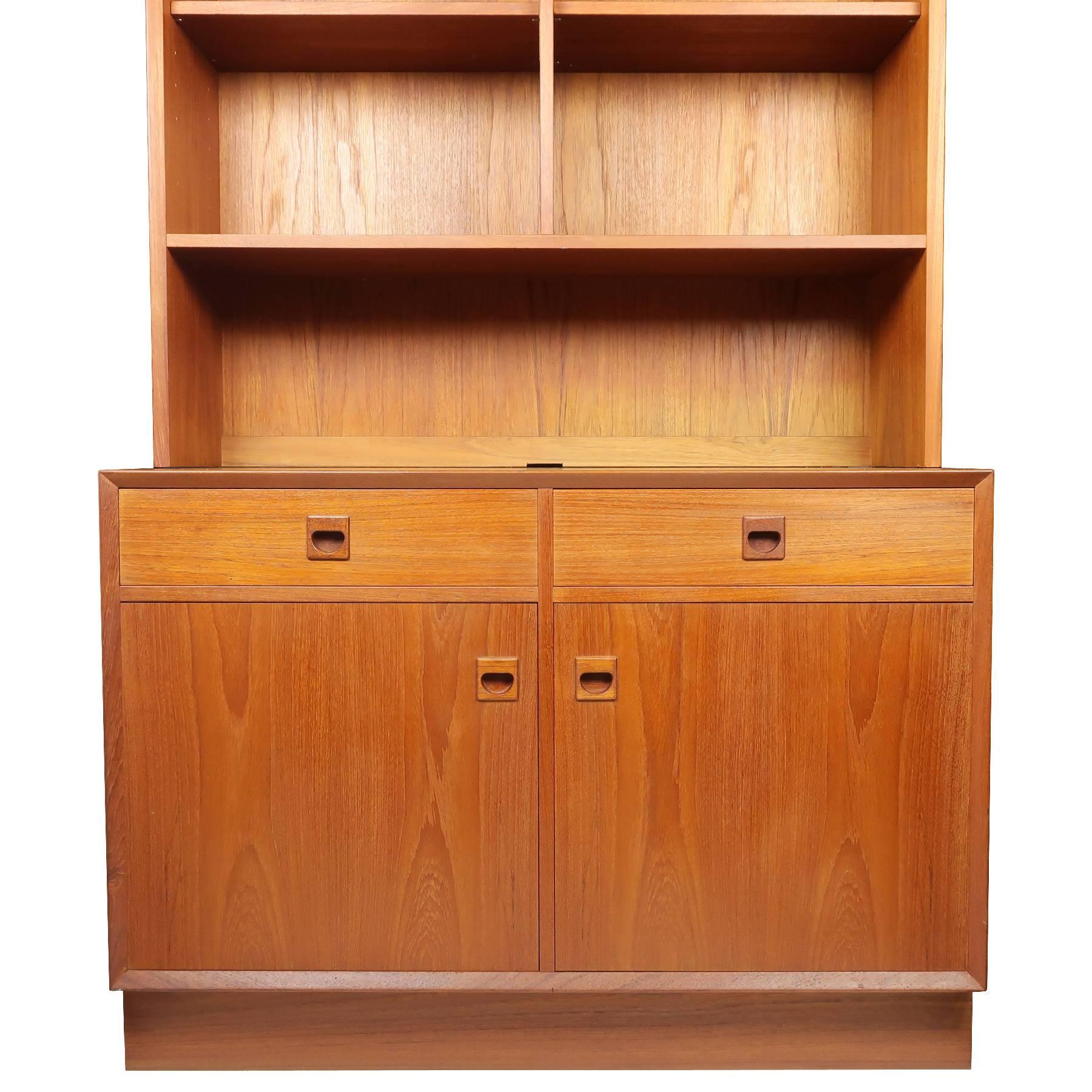 A strikingly lovely teak wall unit designed by Erik Brouer for Brouer Mobelfabrik (Denmark). Rich, warm colored wood with beautiful grain. Features adjustable shelving, two drawers with dovetail joinery, two brass hinged credenza doors, solid teak