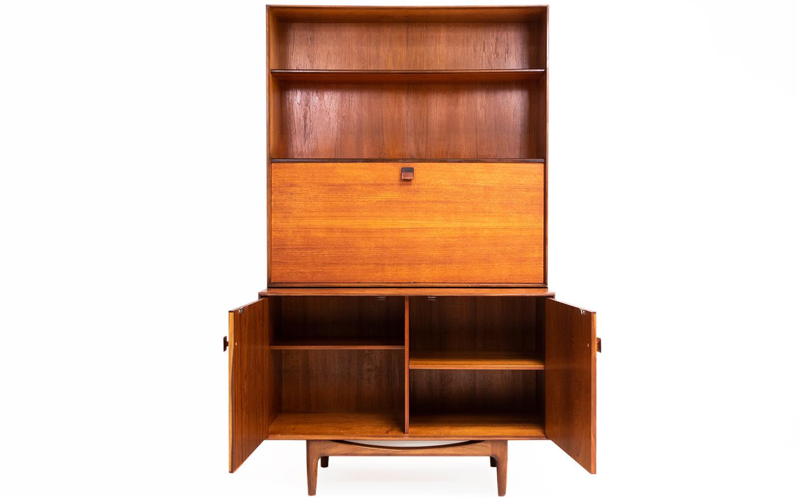 Kofod Larsen wall unit 

Signed 1960s teak wall unit, designed by Ib Kofod-Larsen. 

Made in Great Britain by a Danish designer. The cabinet features two doors with original pull handles and internal shelving. 

A very versatile upper section
