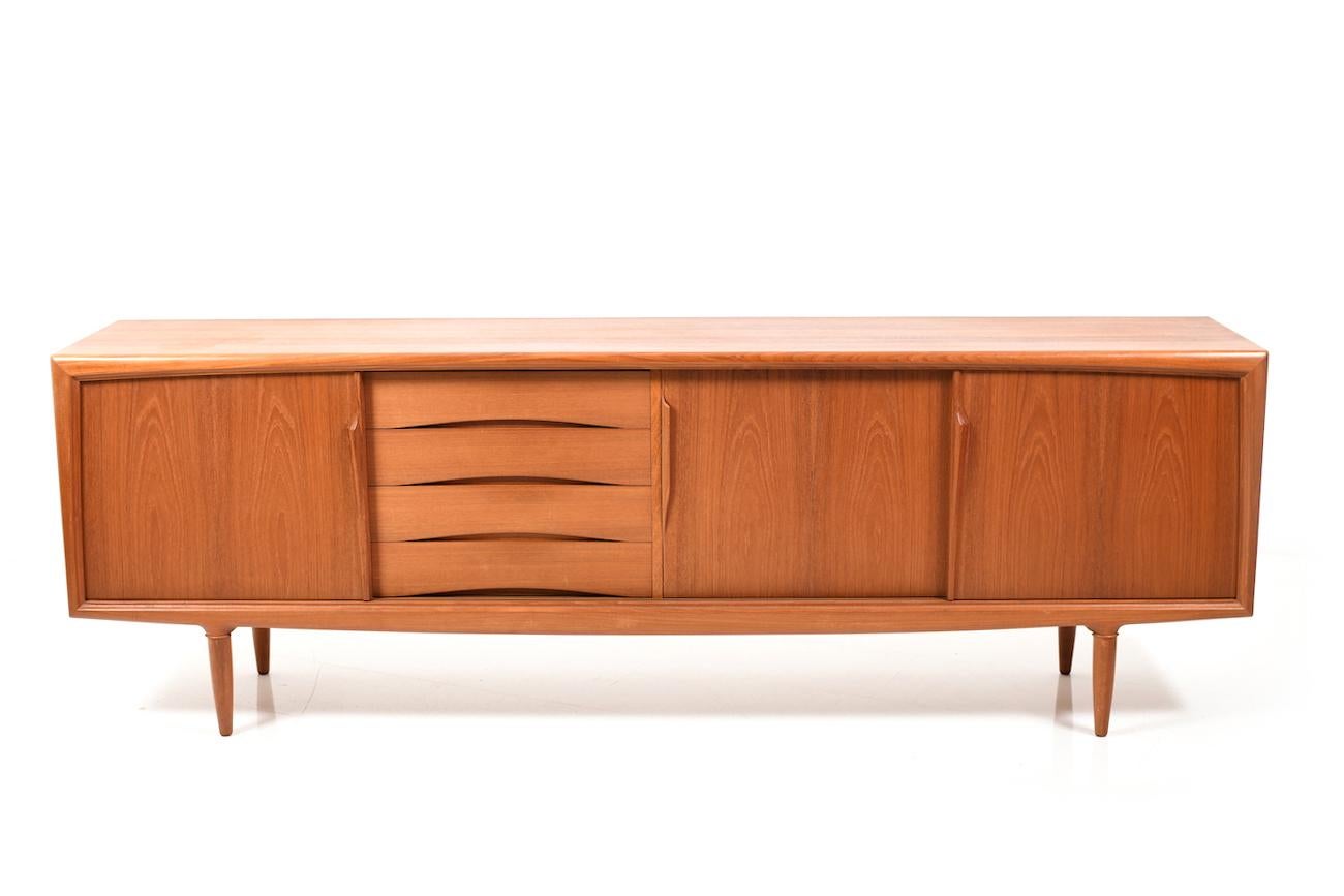 Fine Danish teak wooden credenza or sideboard by Gunni Omann. Manufactured by ACO / Axel Christensen Odder. Four drawers and three sliding doors, behind with shelves. Fine teak in solid and veneer.