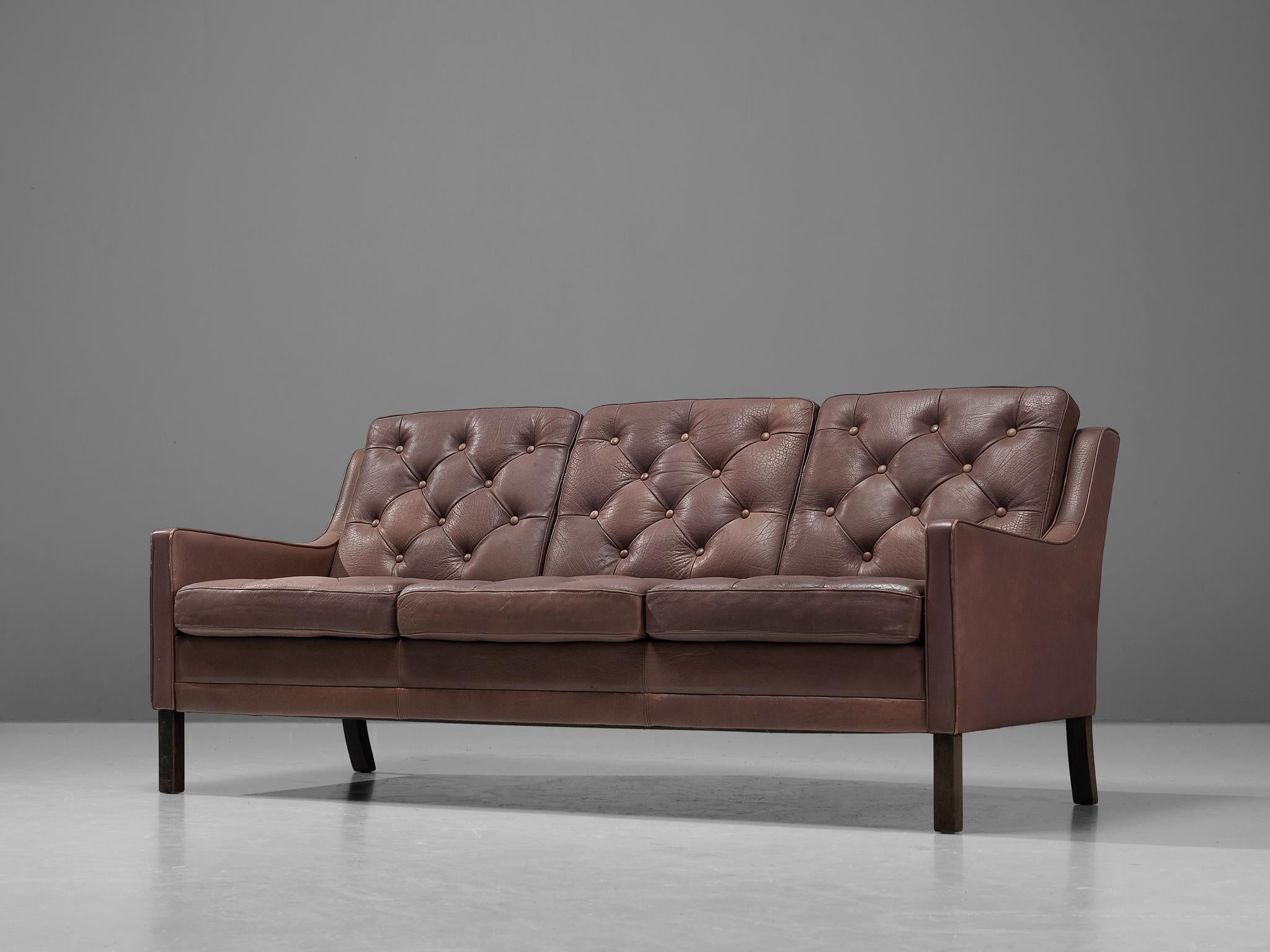 Sofa, Leder, Holz, Dänemark, 1960er Jahre

Dieses Modell erinnert an die Entwürfe von Borge Mogensen. Das braune Leder weist eine leichte Patina auf und ist in sehr gutem Zustand. Die dämmerungsgefüllten Kissen mit Zierknöpfen sorgen für einen