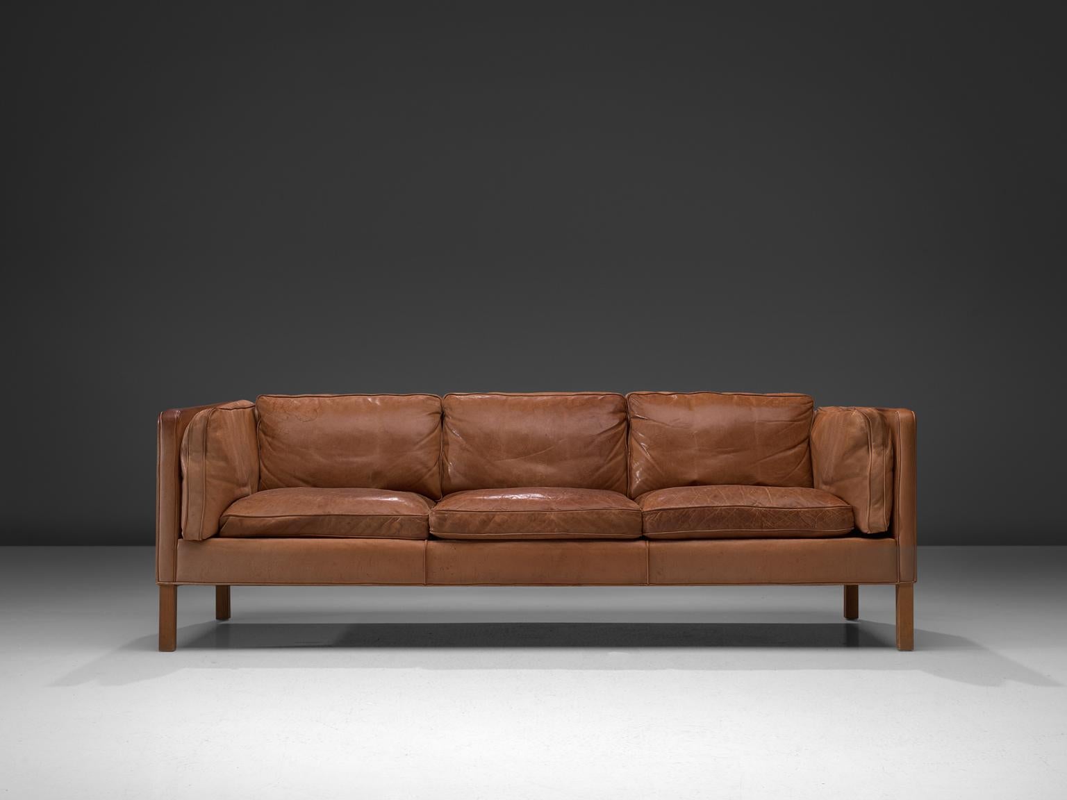 Three-seat sofa, cognac leather and oak, Denmark, 1960s.

This design comes from the 1960s and has wonderful shapes and comfort. The three-seat sofa comes with loose cushions in seating, back and sides. They are stuffed with fluff and show a nice