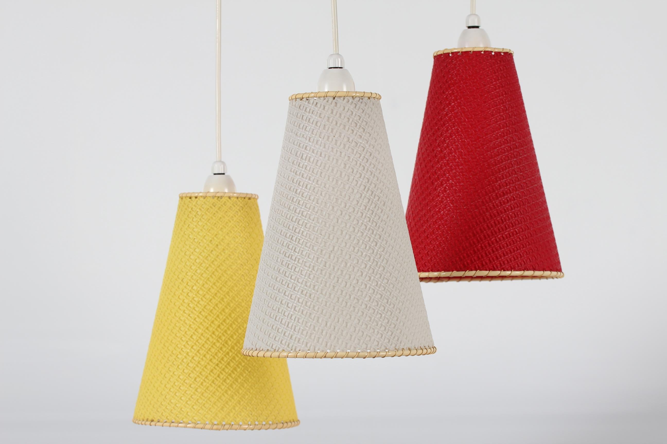 Cozy retro tri-color pendant light with three shades from the 1960s. The shades are mounted on a frame of teak, from which they hang. The plastic shades are white, yellow and red.

Measures: Total height 100 cm
Height lampshades 24 cm
Diameter