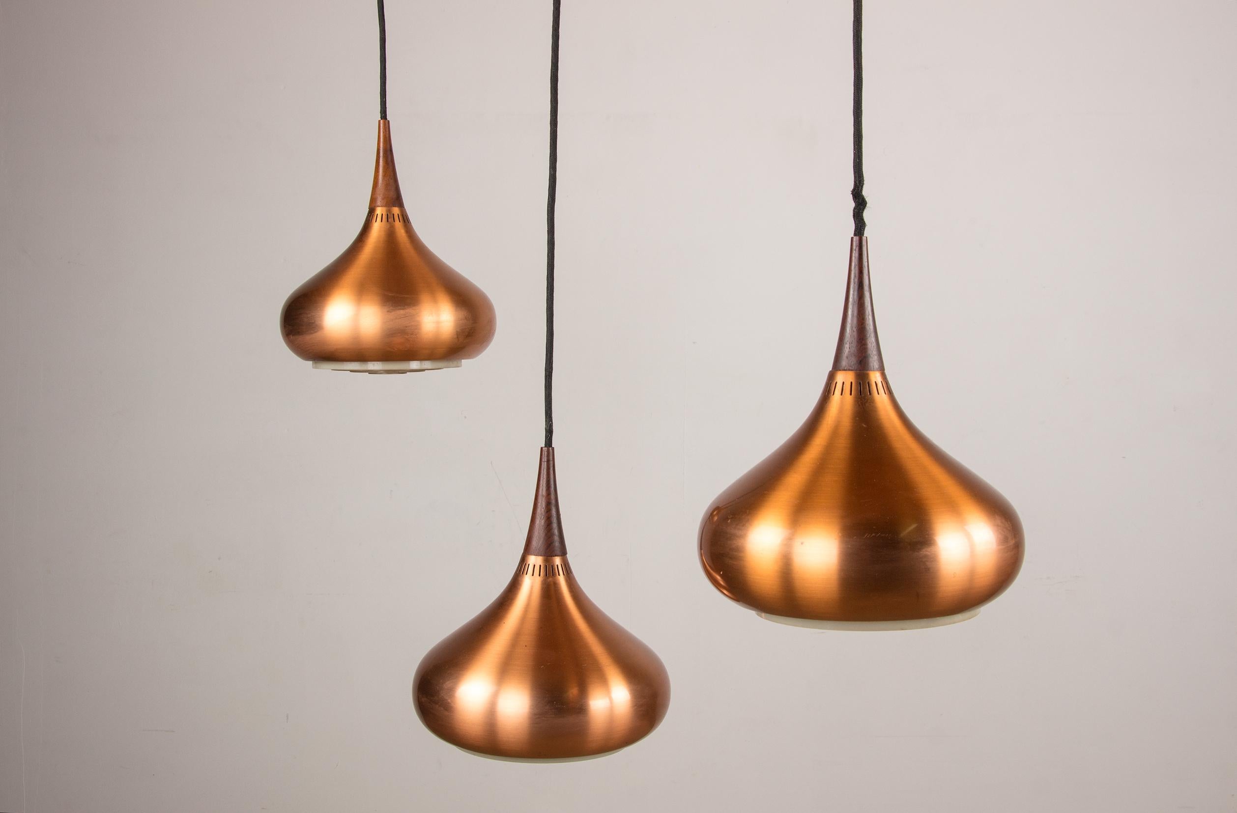 Magnificent large Scandinavian pendant light. 3 copper-plated metal bulbs each topped with a rosewood cone and connected above by a rosewood bar. Superb sober and elegant design. The whole thing is adjustable and adjustable in height to illuminate a